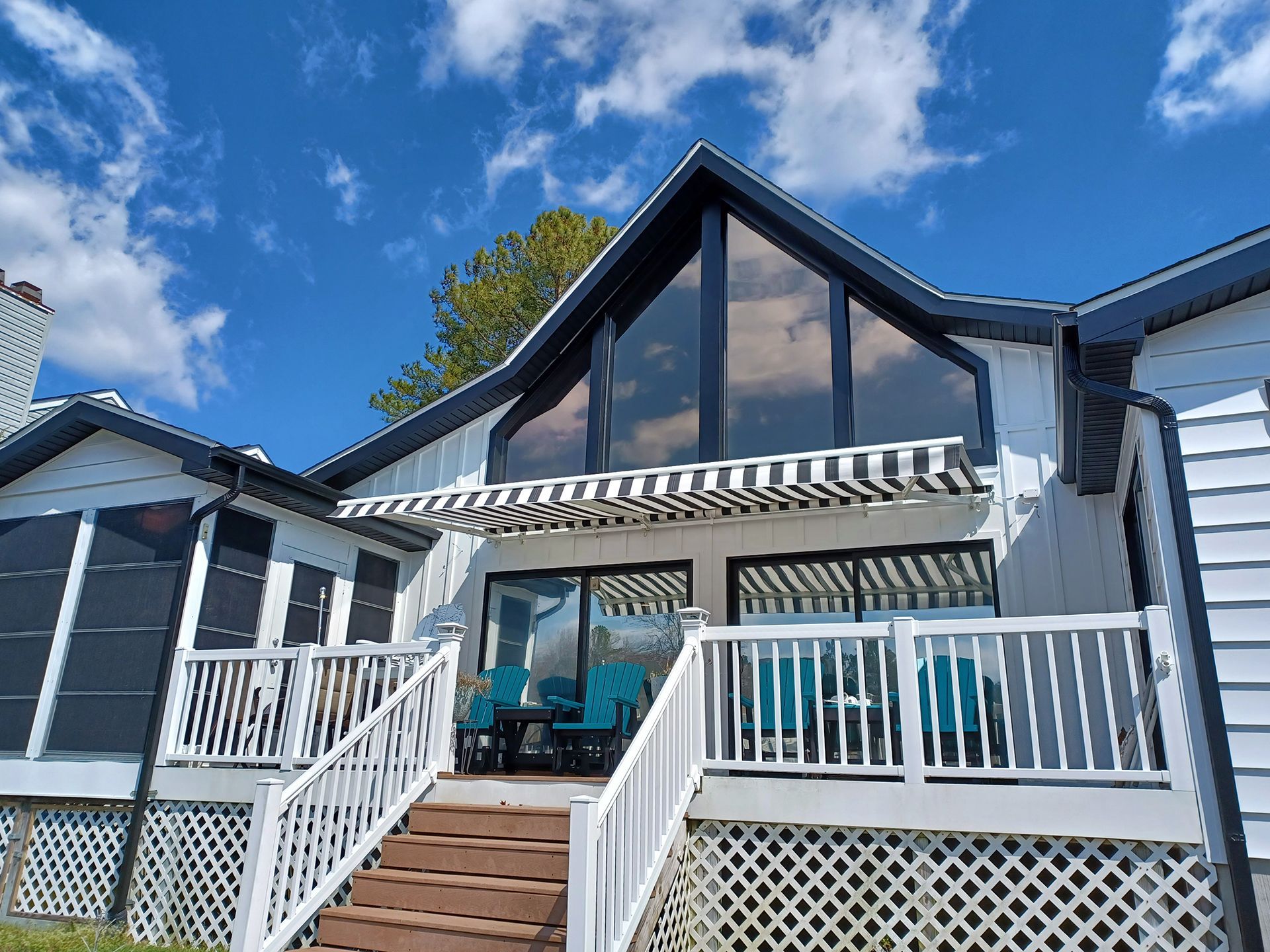 A white house with a large deck and awning
