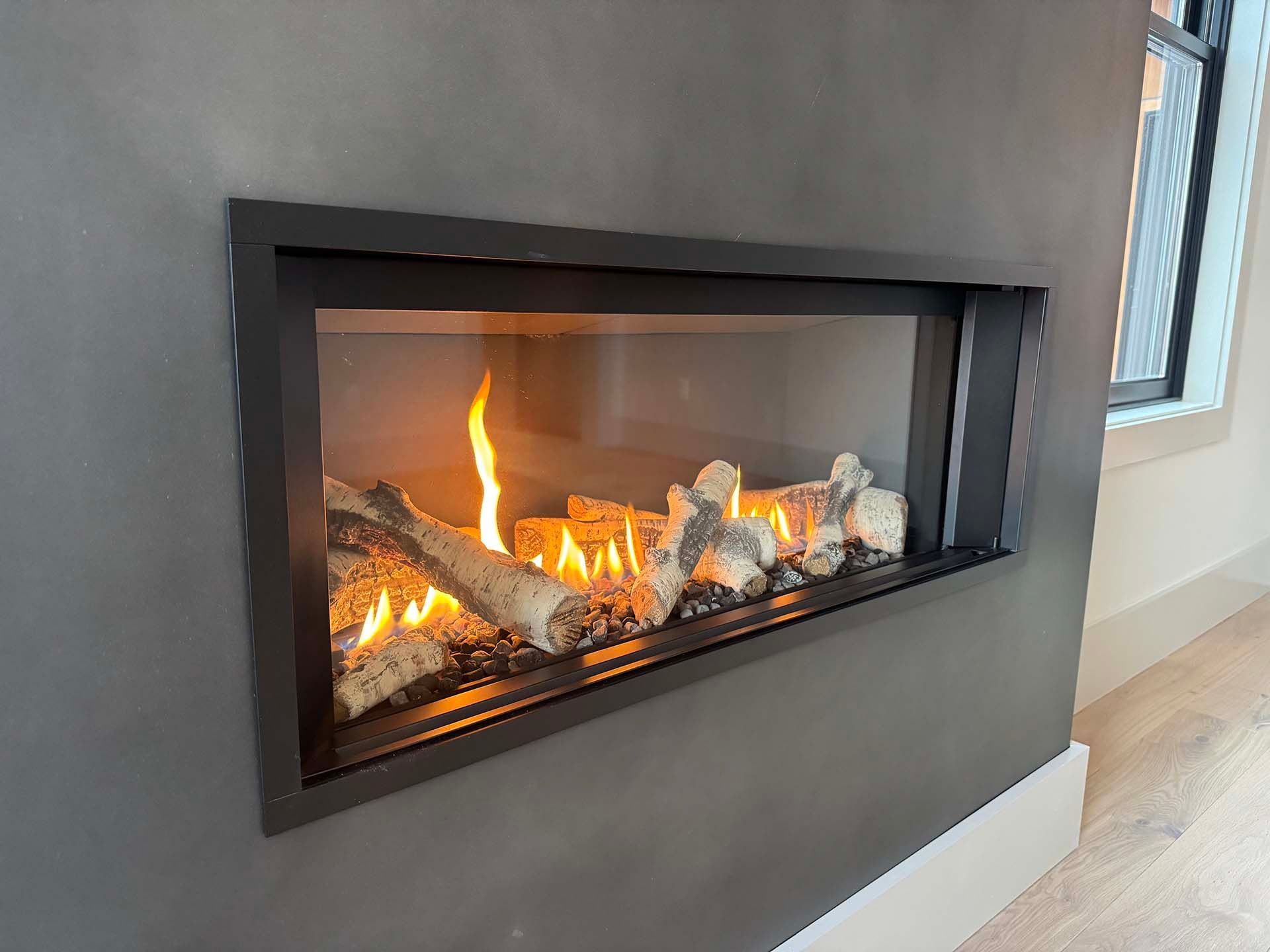 A fireplace with logs in it is lit up in a living room.