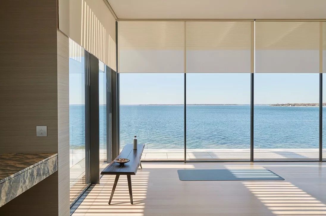 There is a table in the middle of the room with a view of the ocean.