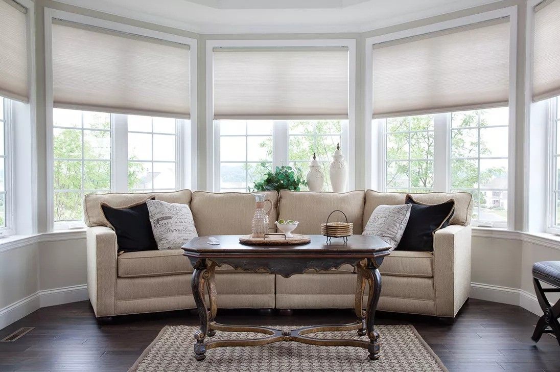 A living room with a couch, coffee table, and lots of windows