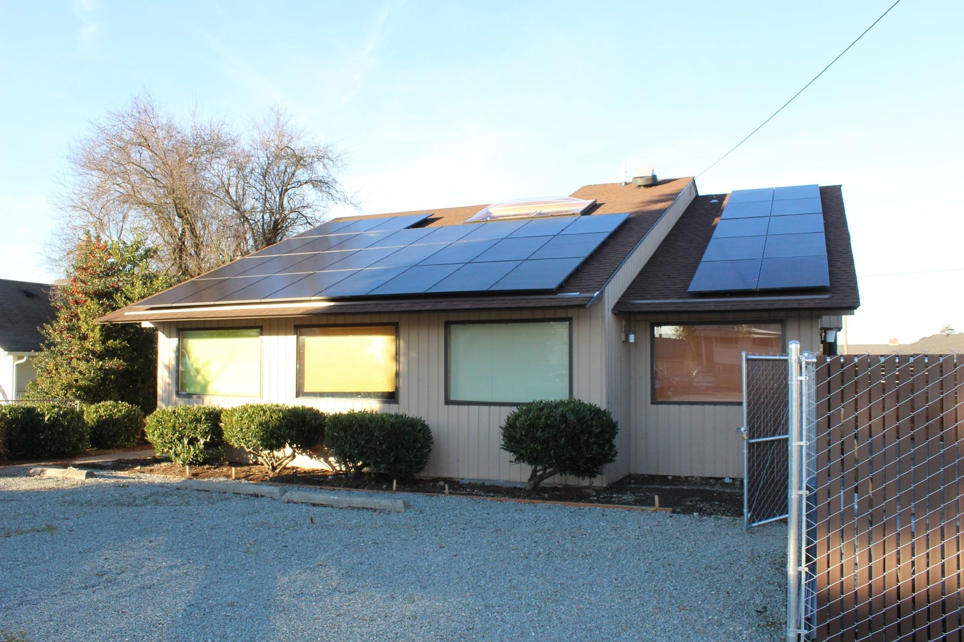 a house with solar panels on the roof and a chain link fence