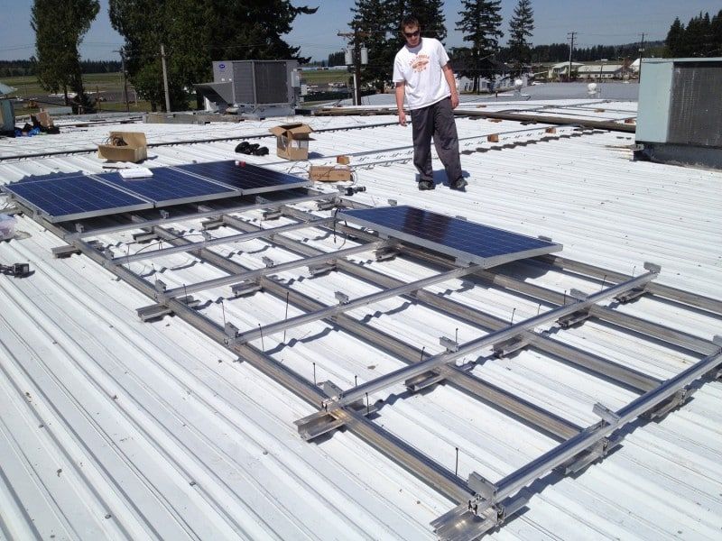 a man standing on top of a roof with solar panels on it