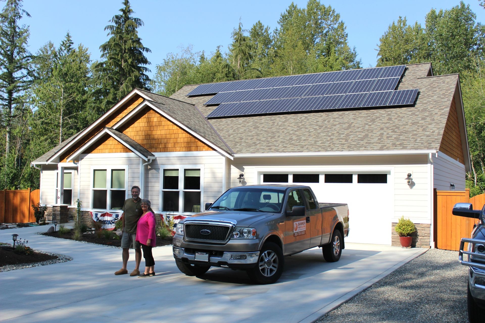 a man and woman are standing in front of a house with solar panels on the roof