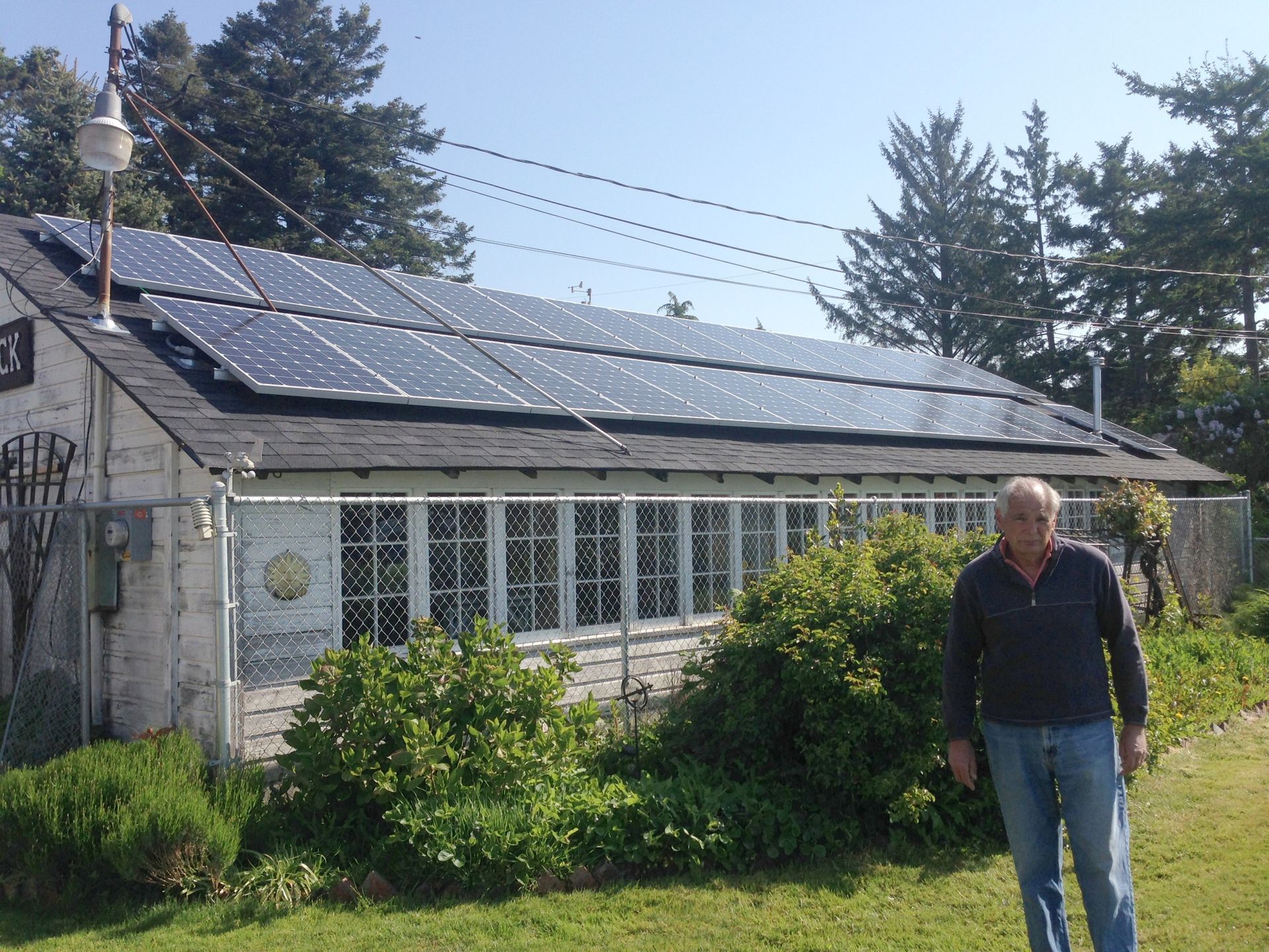 a man standing in front of a house with solar panels on the roof