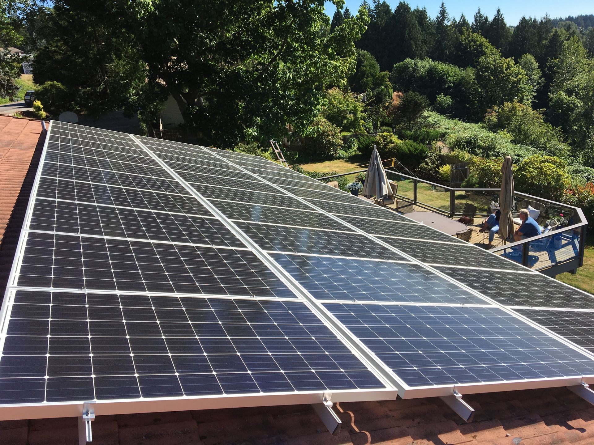 a row of solar panels on a roof with trees in the background
