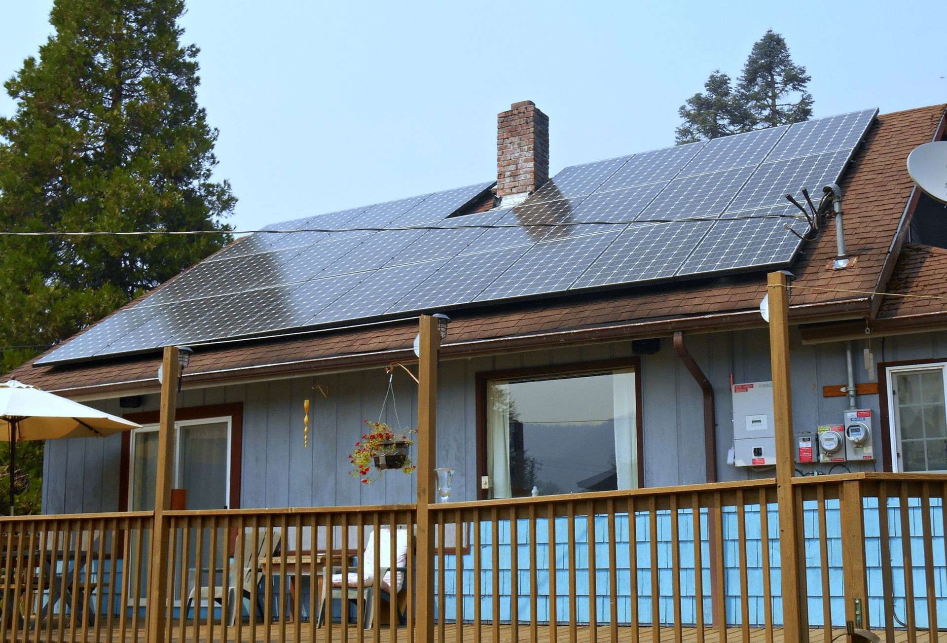 a house with solar panels on the roof and a wooden deck