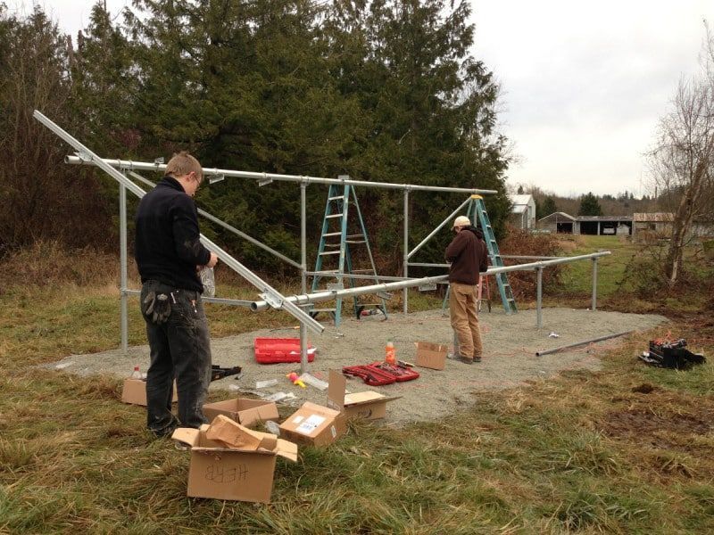 two men are working on a metal structure in a field