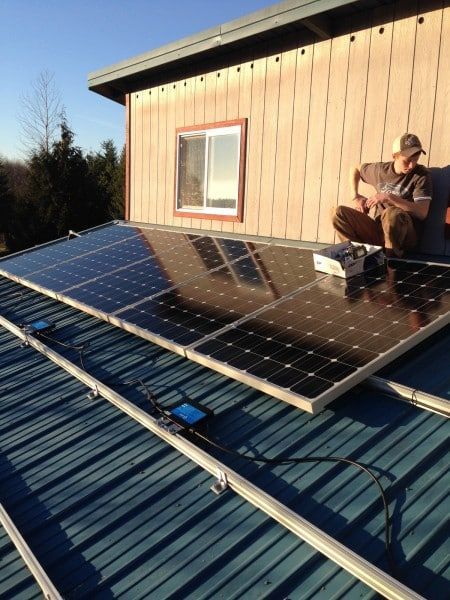 a man sits on top of a roof with solar panels