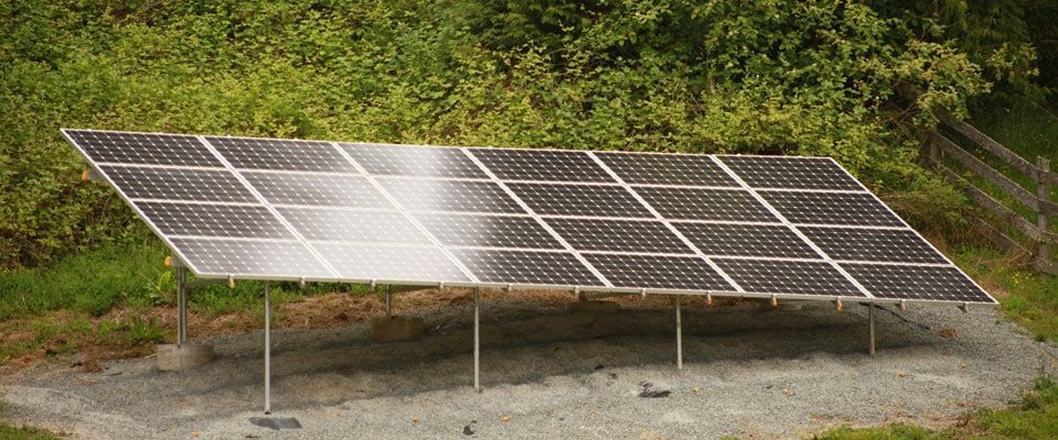 a row of solar panels sitting on top of a dirt field
