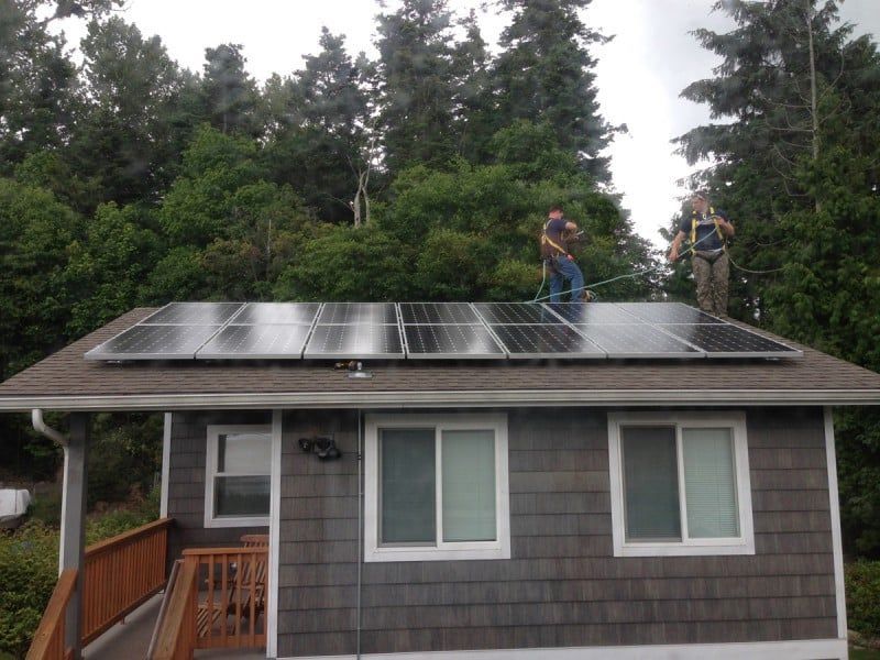 two men are installing solar panels on the roof of a house