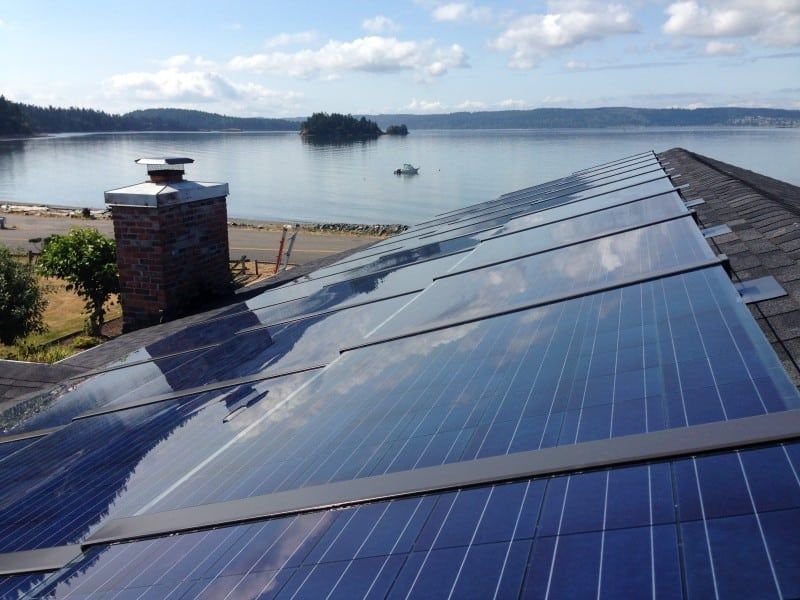 a row of solar panels on a roof overlooking a lake