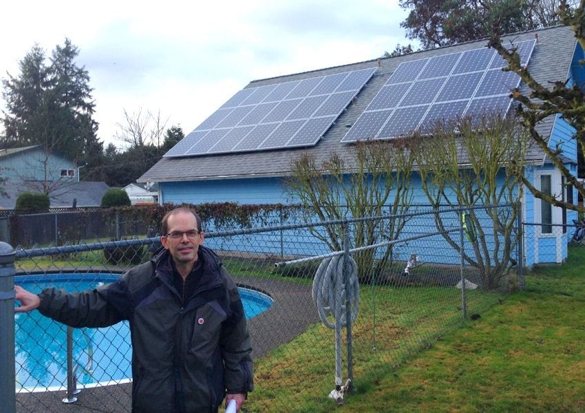 a man is standing in front of a house with solar panels on the roof