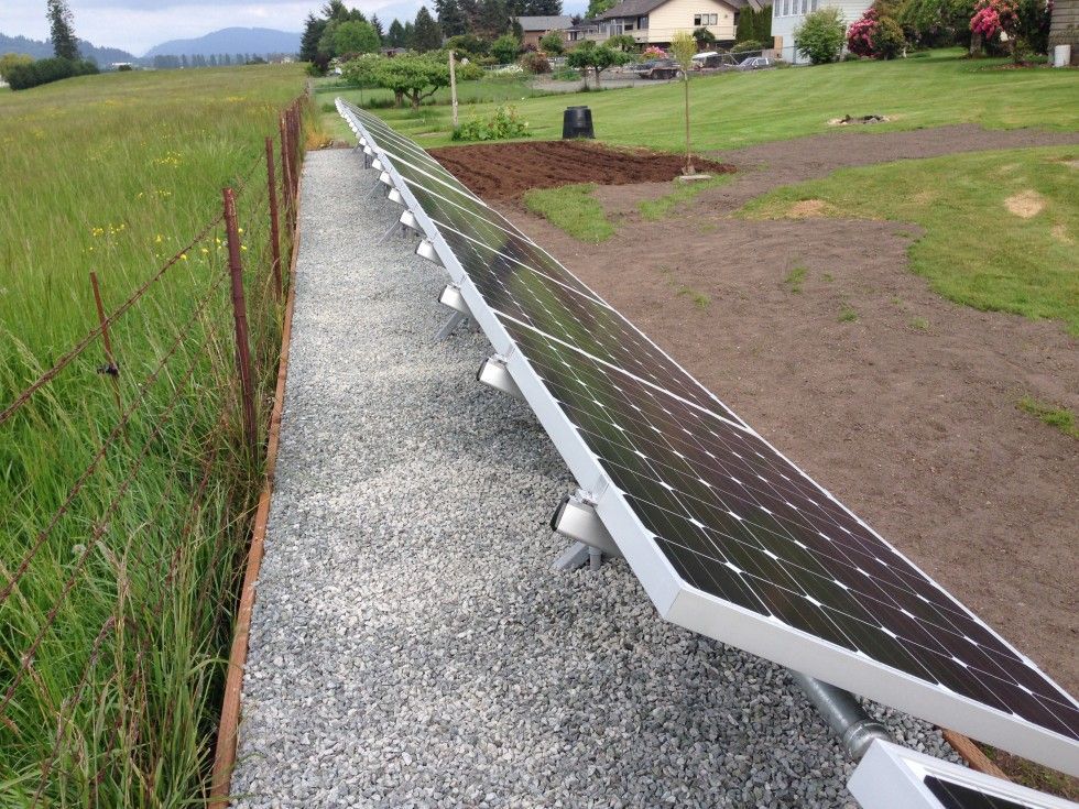 a row of solar panels sitting next to a gravel path