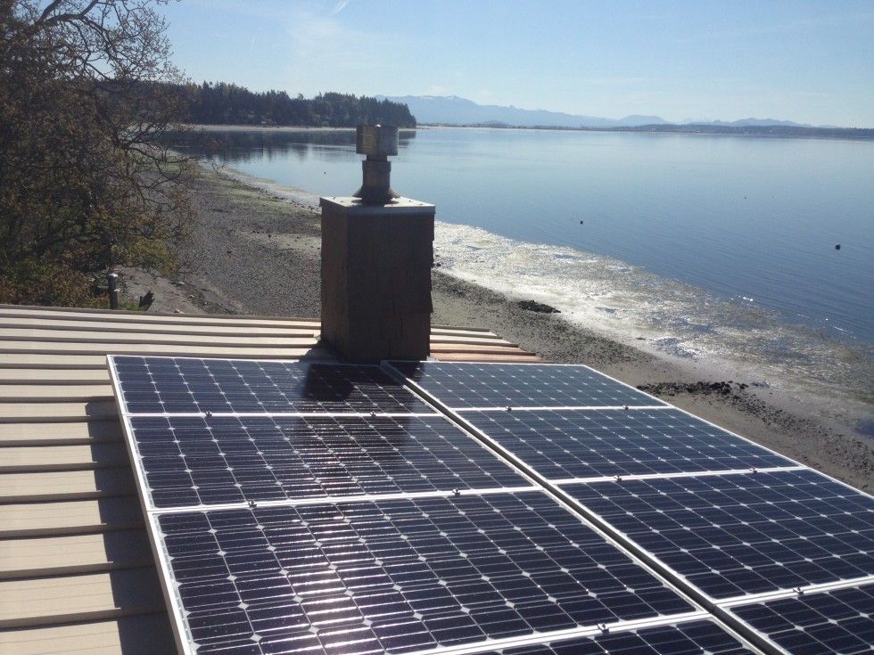 a row of solar panels on a roof overlooking a body of water