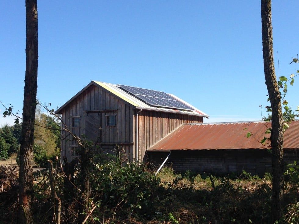 a wooden barn with solar panels on the roof