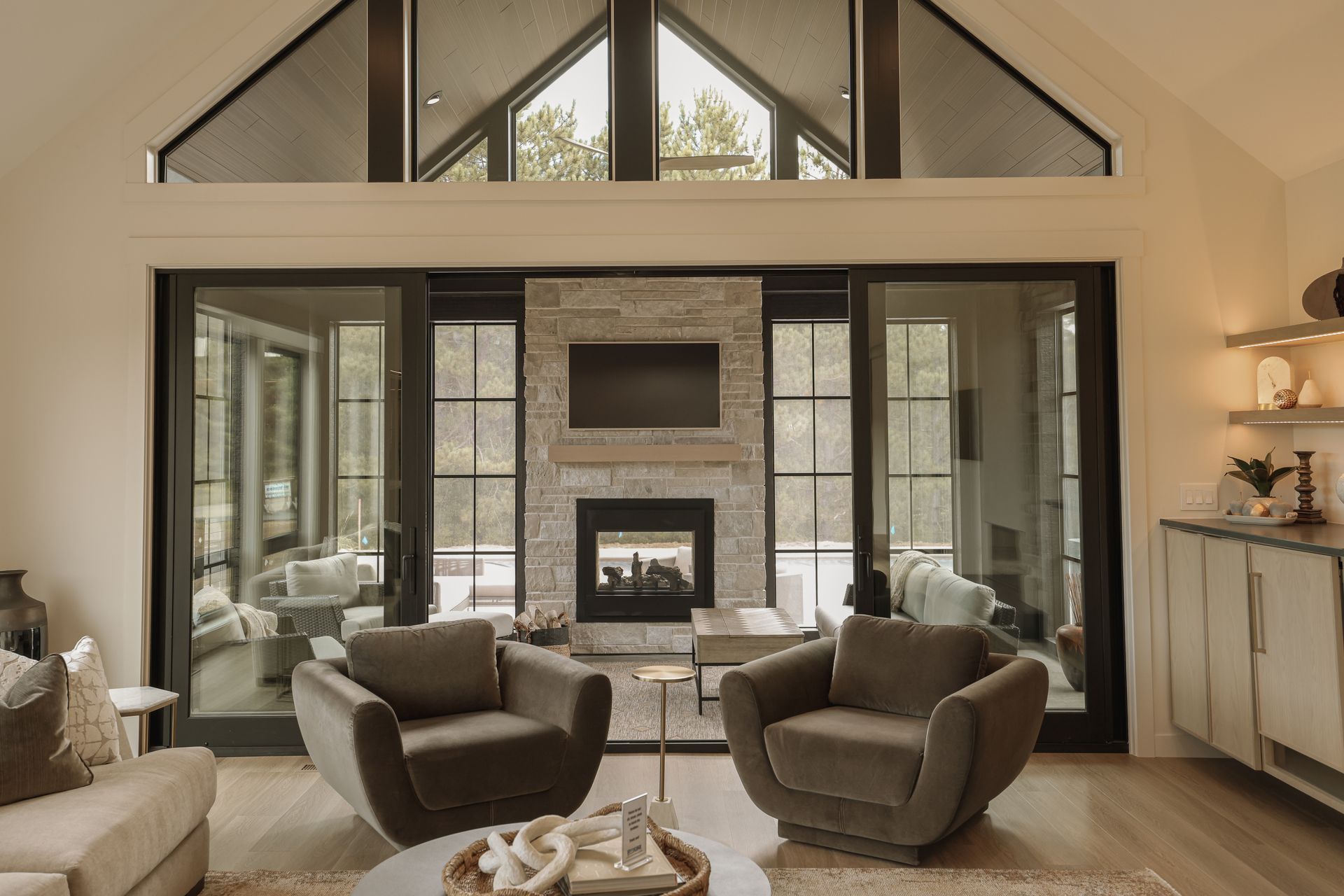 Living room with fireplace, sliding glass doors, and two gray armchairs.
