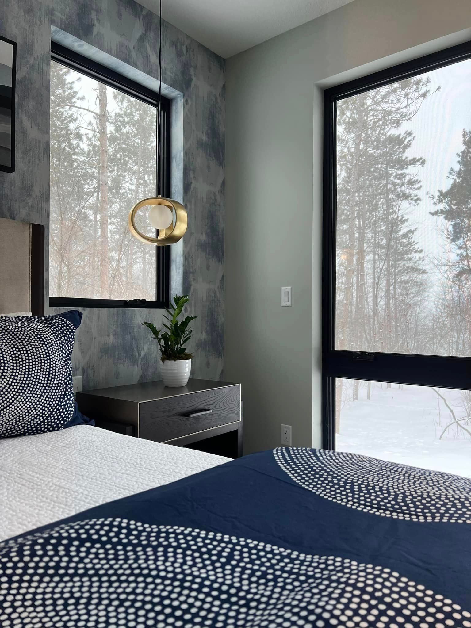 A bedroom with a bed, nightstand, and two windows.