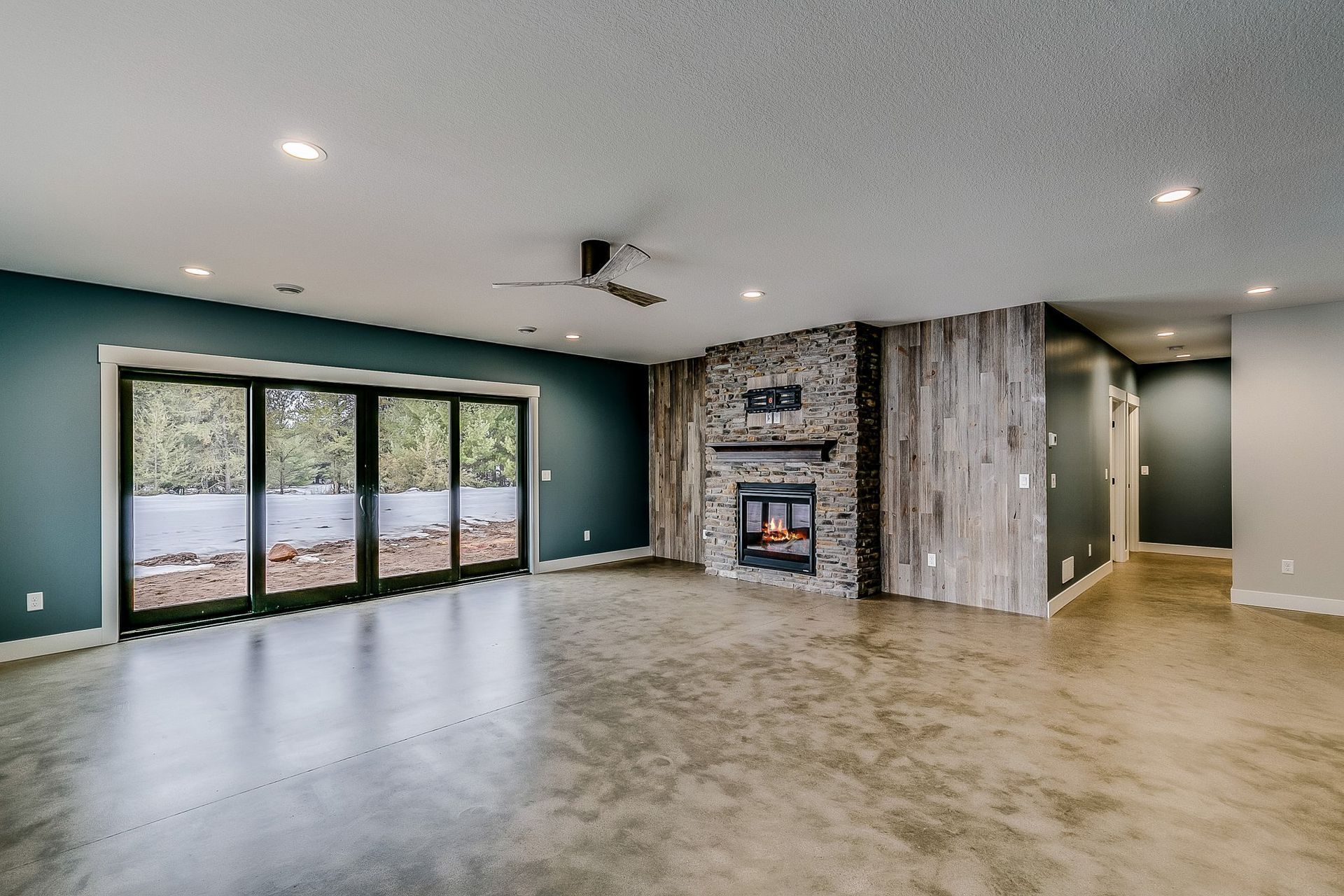 An empty living room with a fireplace and sliding glass doors.