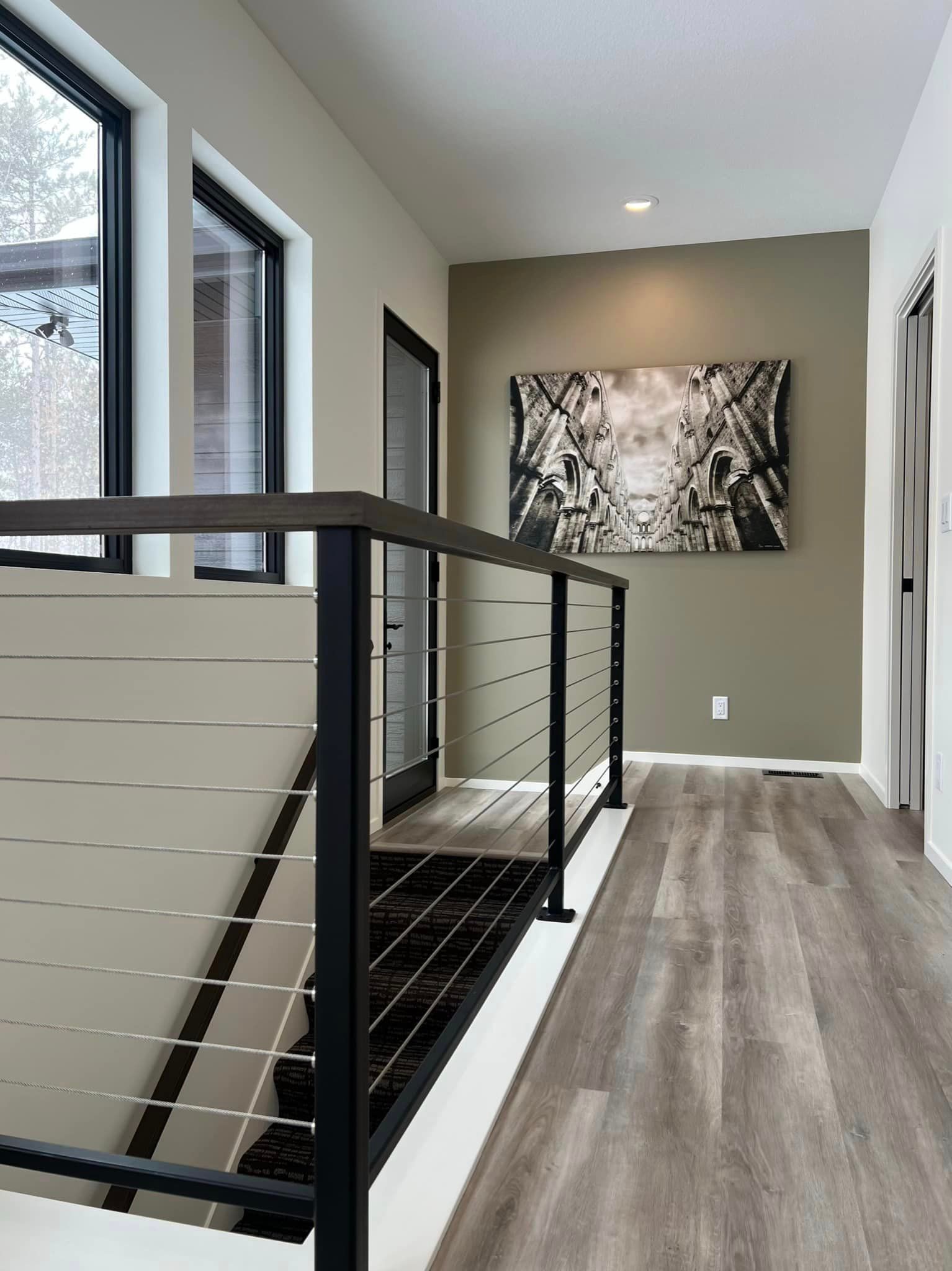 A hallway with a staircase and a painting on the wall.