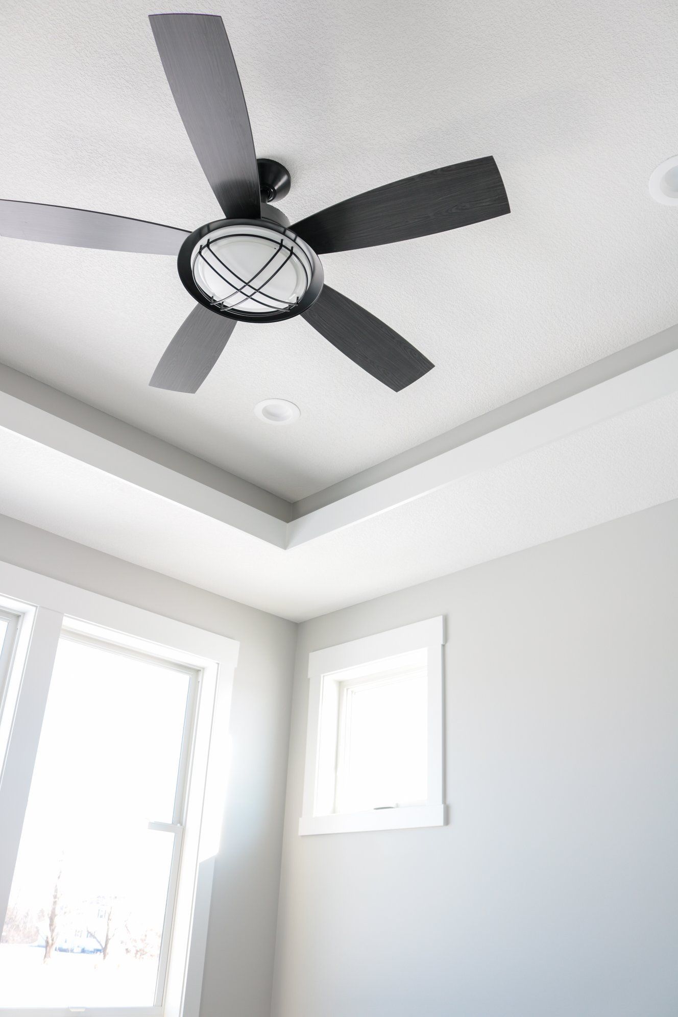 A ceiling fan is hanging from the ceiling of a room next to a window.