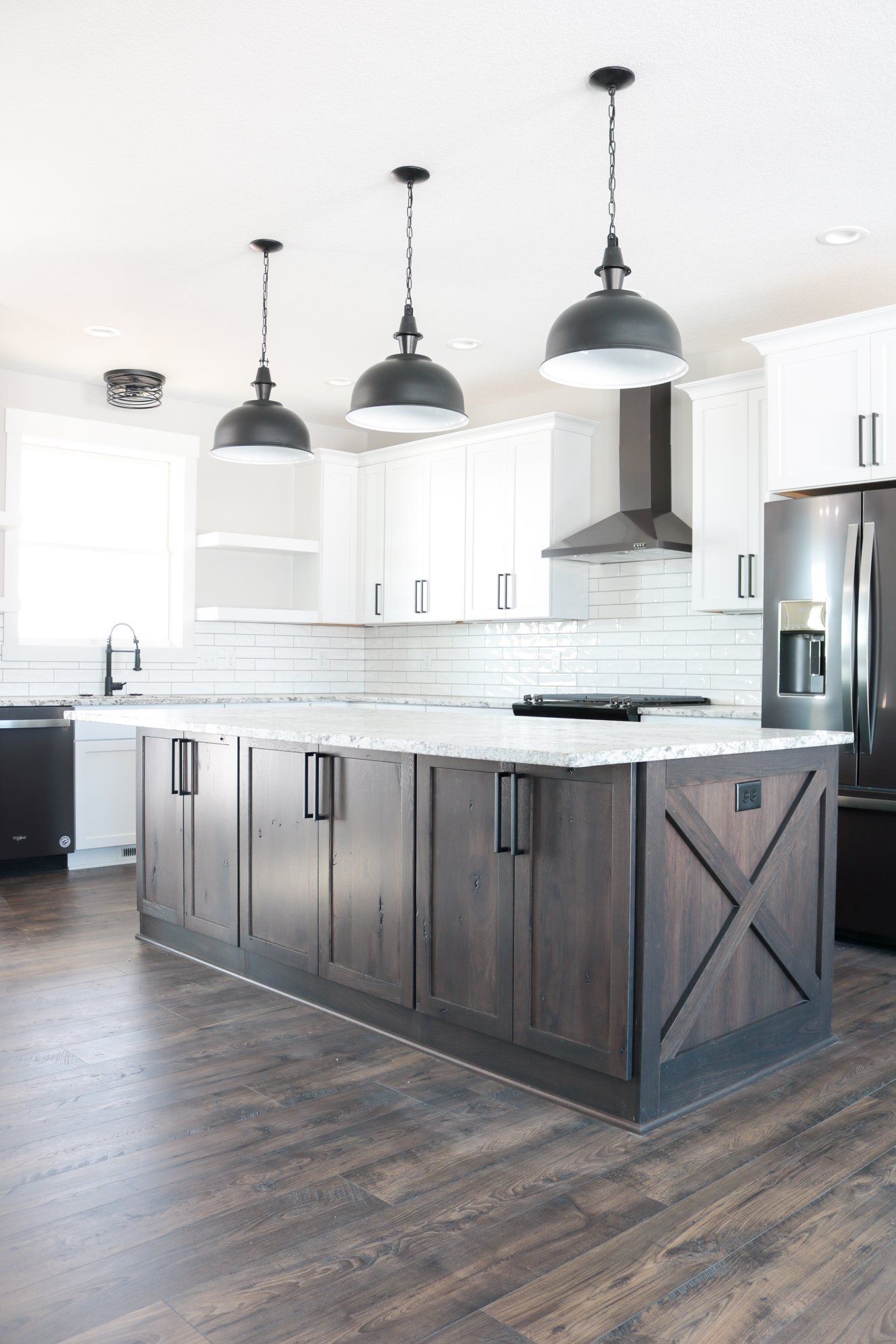 A kitchen with white cabinets, black appliances, and a large island.