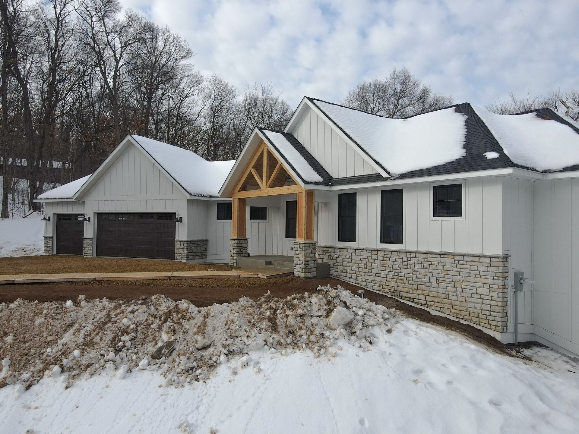 A white house with a black roof is covered in snow.