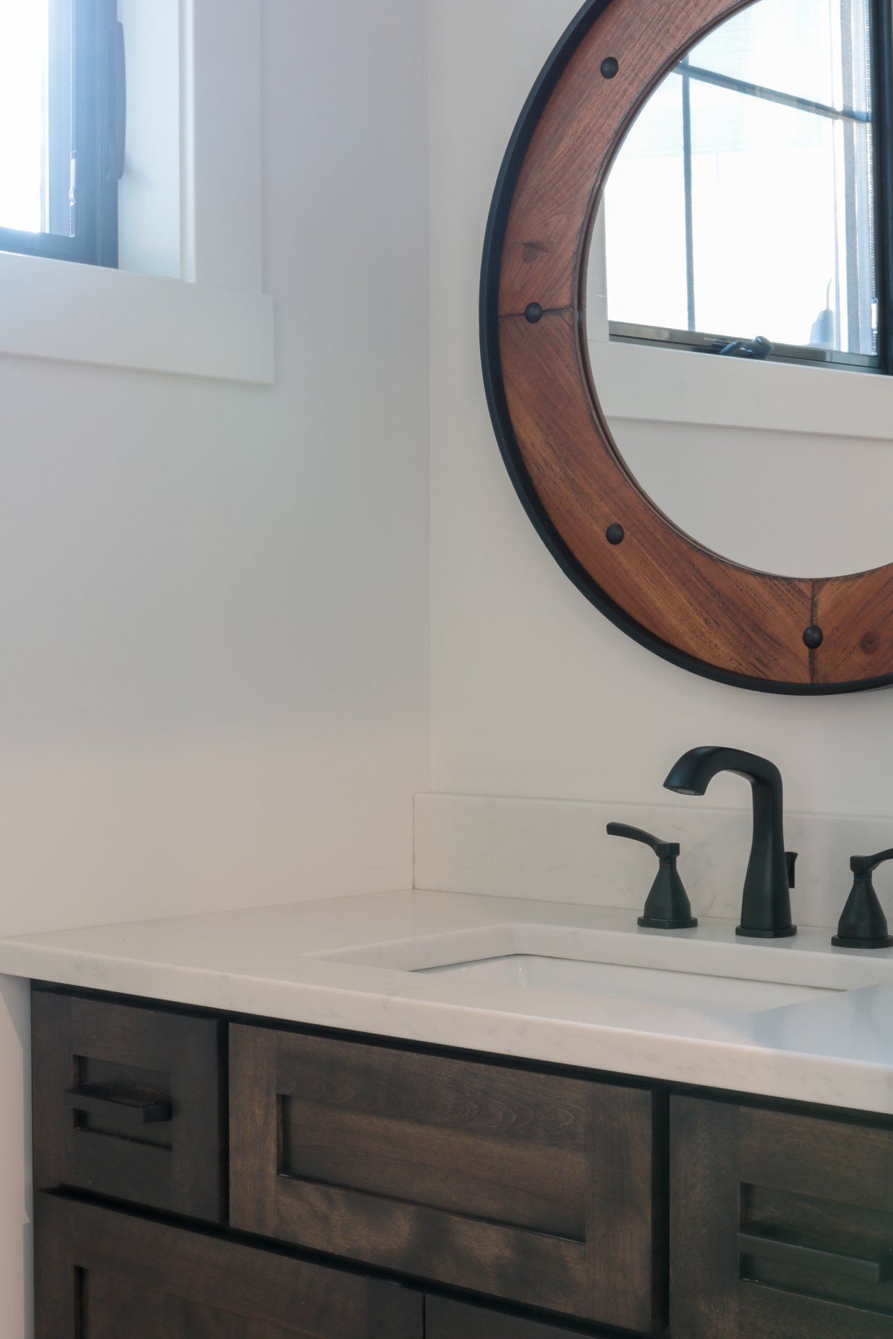 A bathroom sink with a round mirror above it.