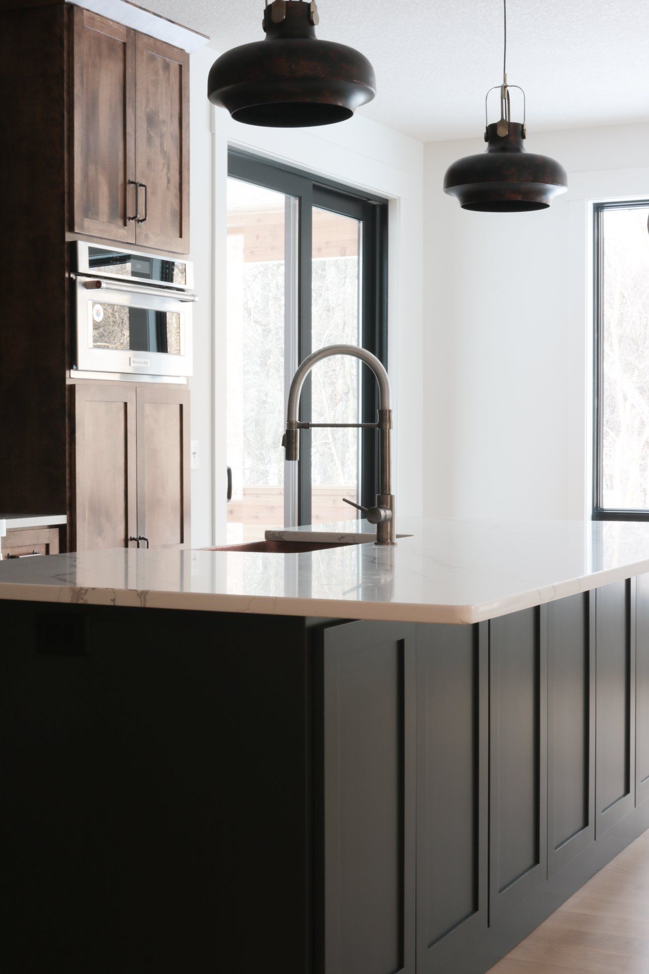 A kitchen with black cabinets , a sink , and a window.