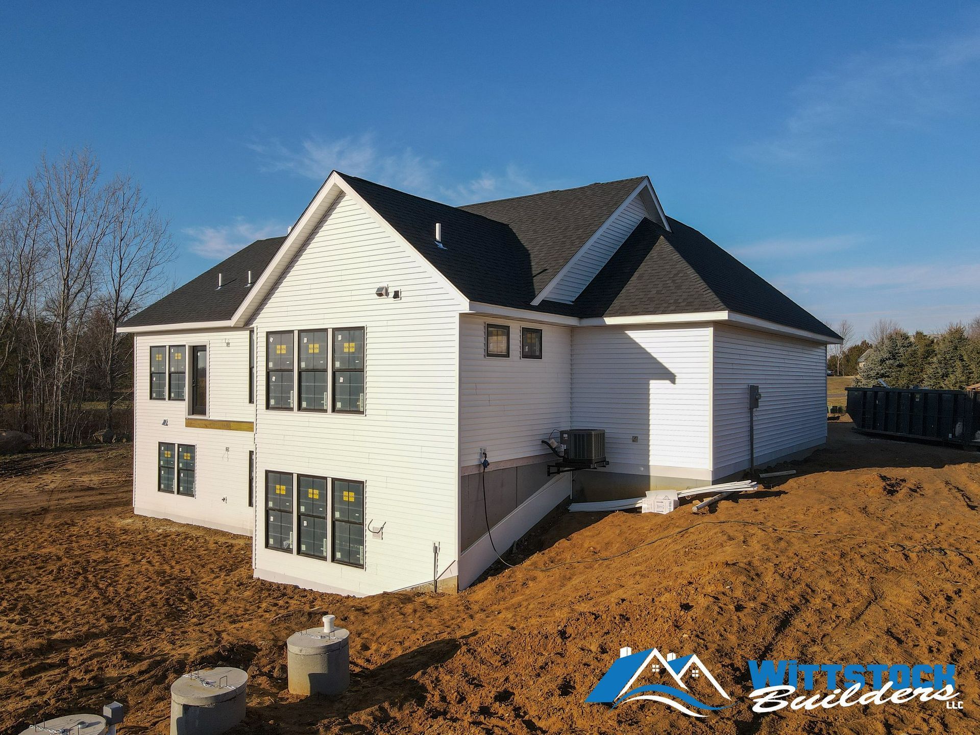 A large white house is being built in a dirt field.