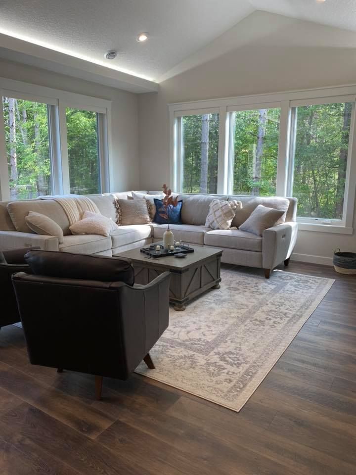 A living room with a sectional couch, two chairs, a coffee table and a rug.
