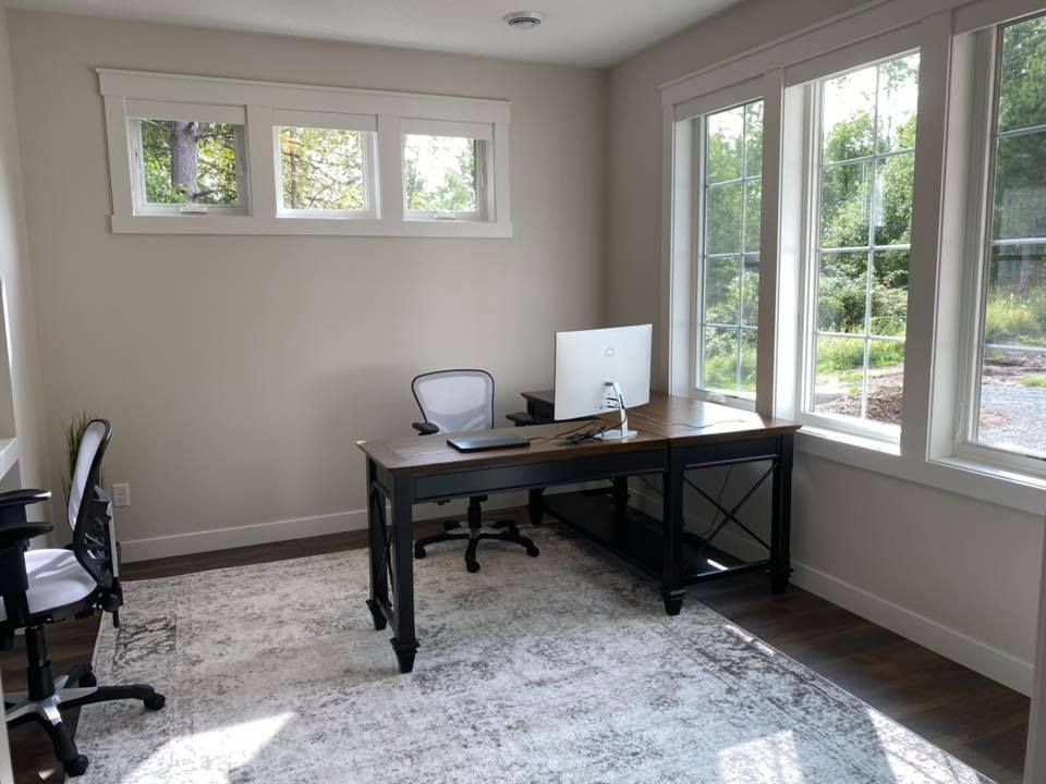 A home office with a desk and chairs and a computer on it.