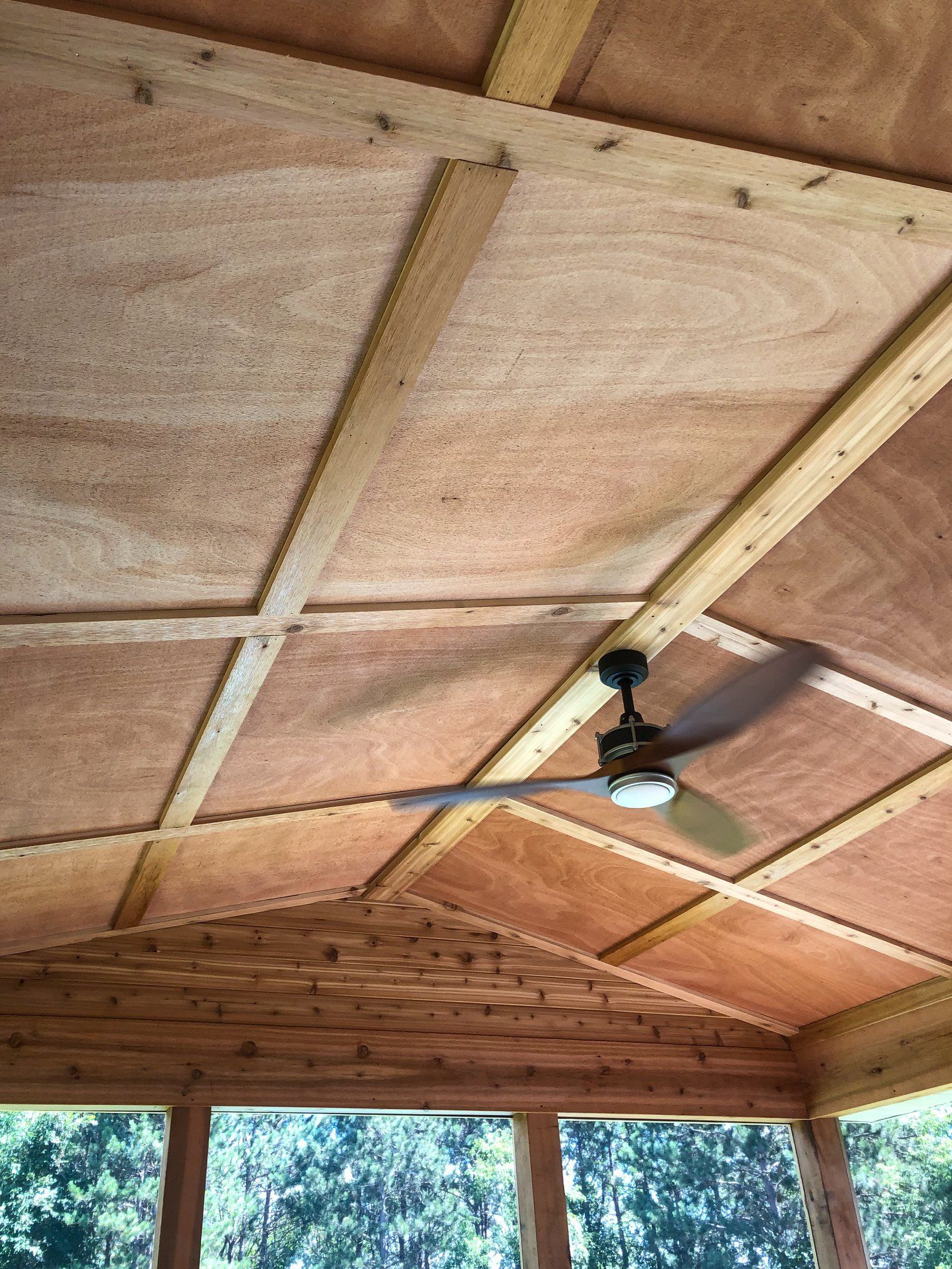 A ceiling fan is hanging from the ceiling of a wooden room.