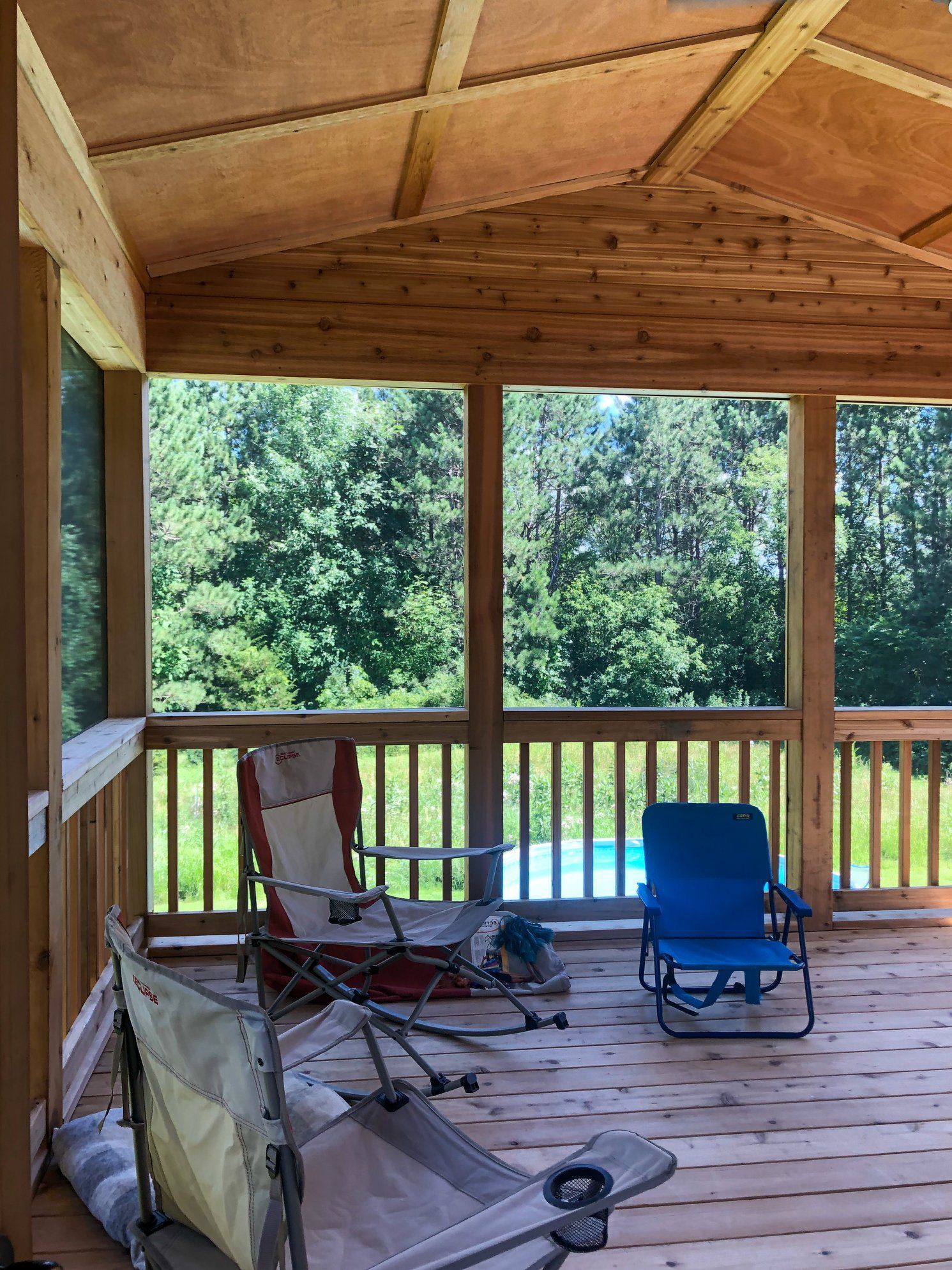 A screened in porch with chairs and a stroller.