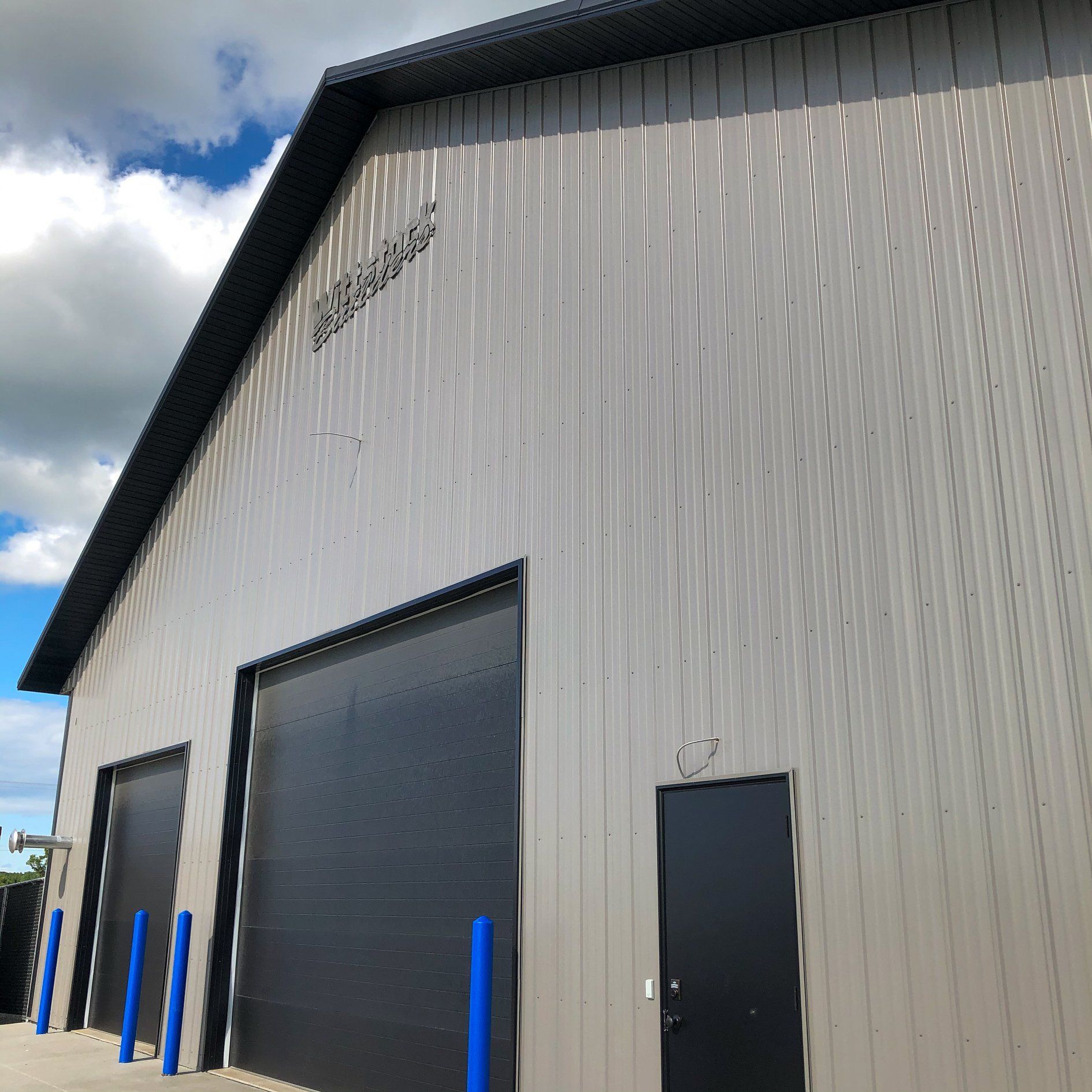 A large building with black doors and blue poles in front of it.