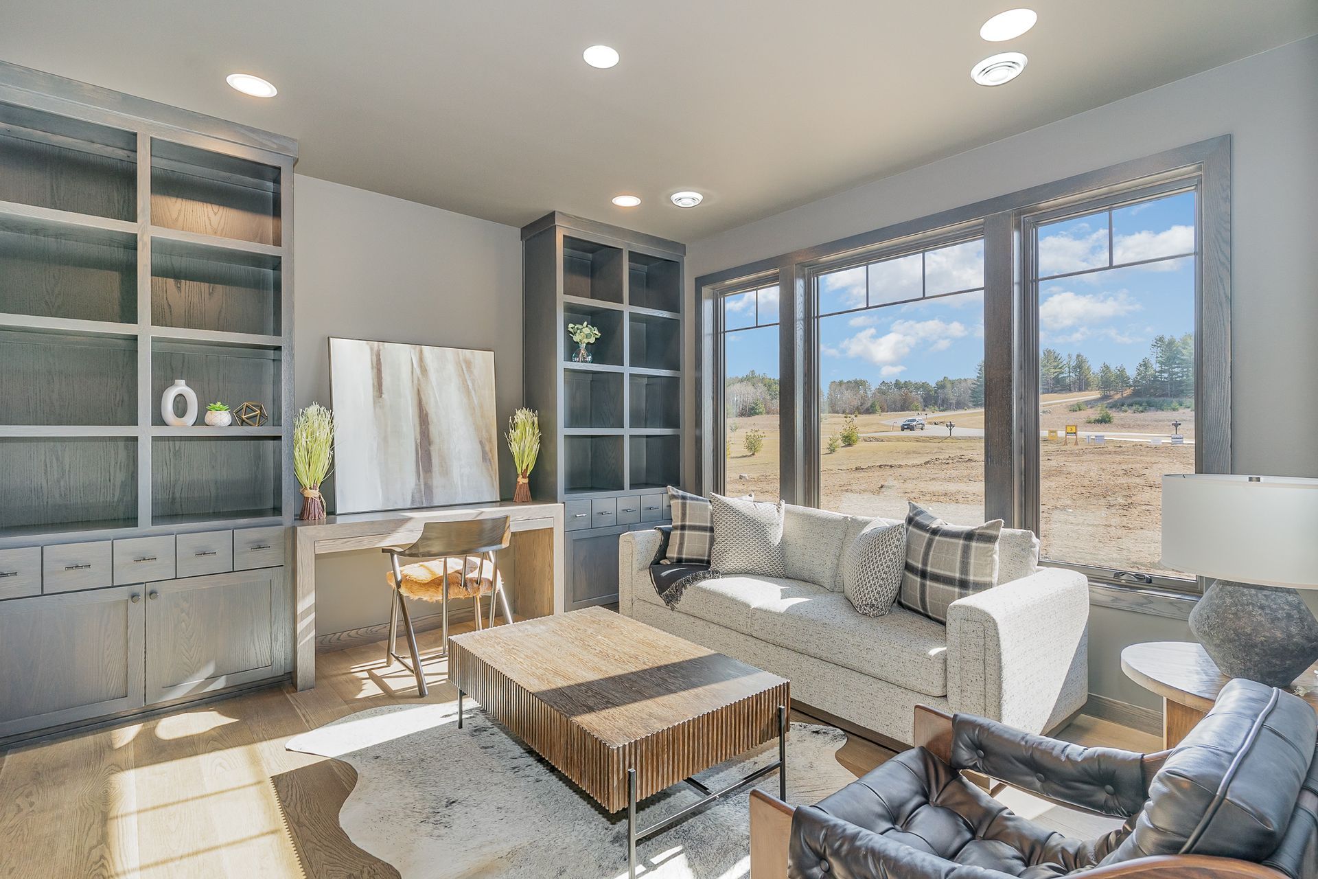 A living room with a couch, chair, coffee table and lots of windows.