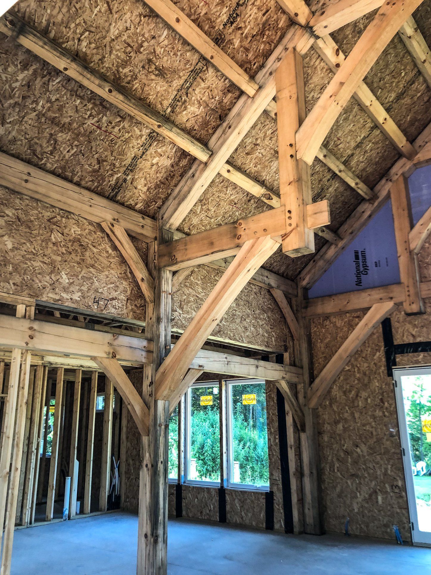 The inside of a building under construction with wooden beams and windows.