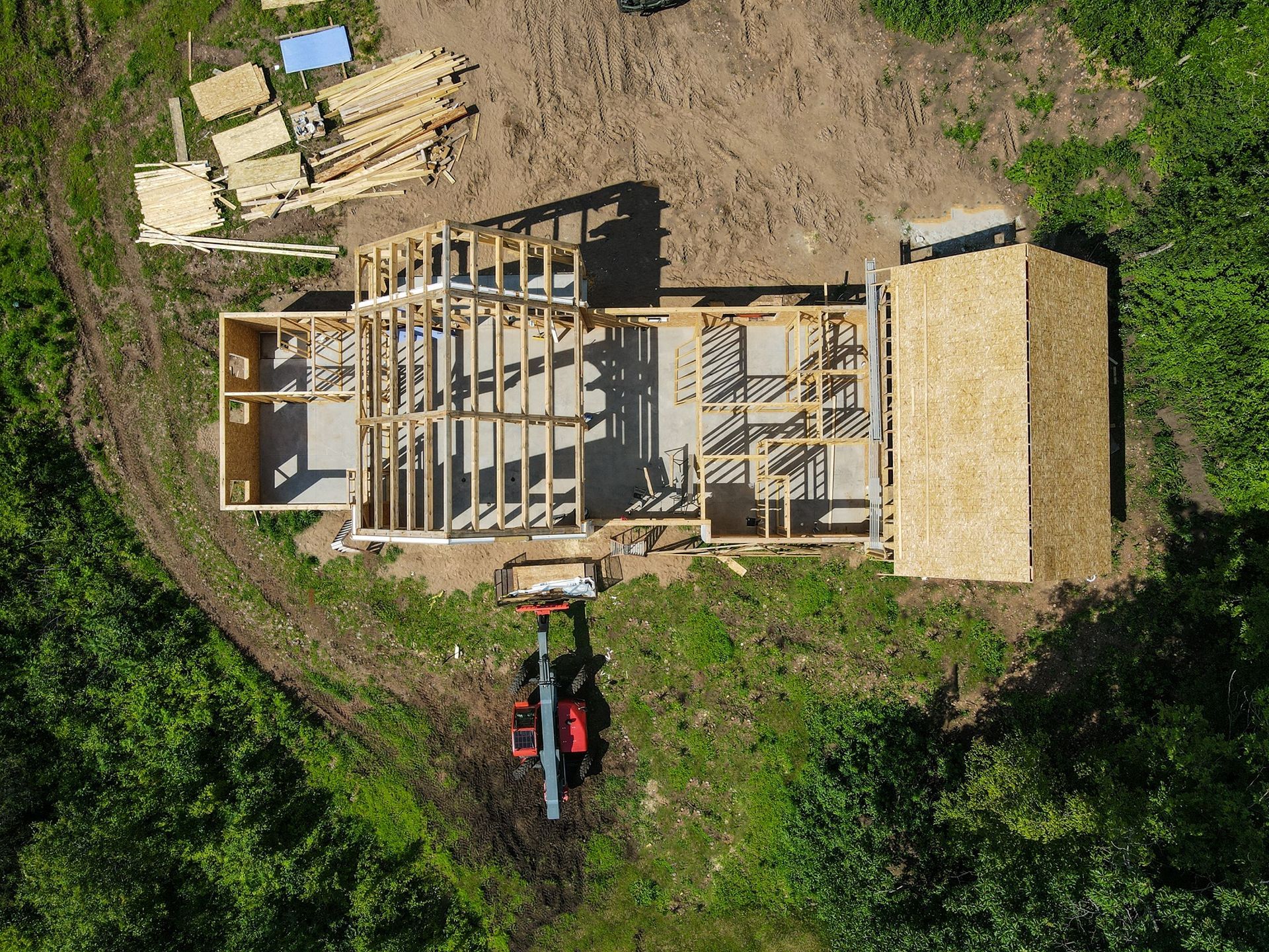 An aerial view of a house under construction in the middle of a forest.