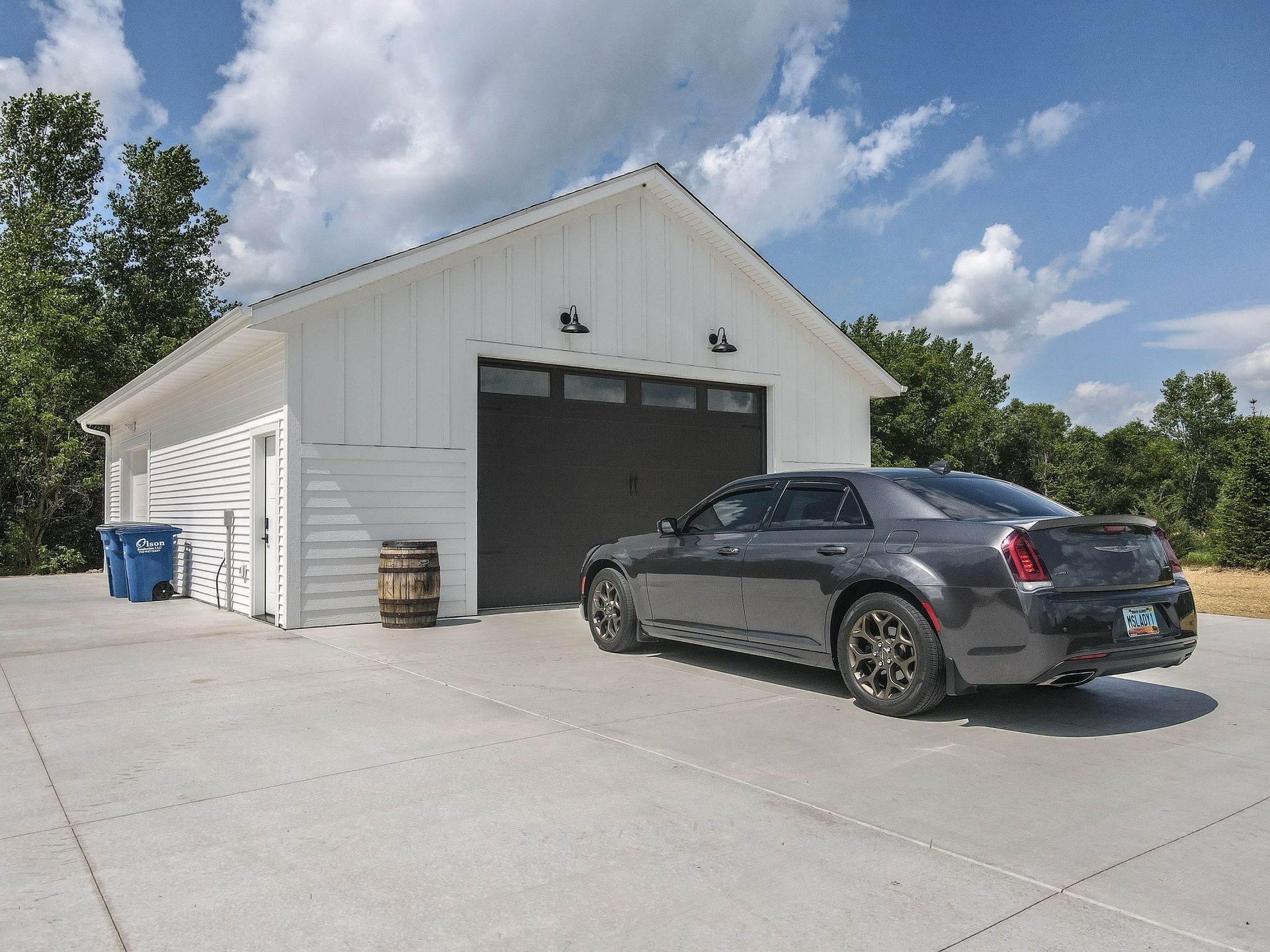 A gray car is parked in front of a white garage.