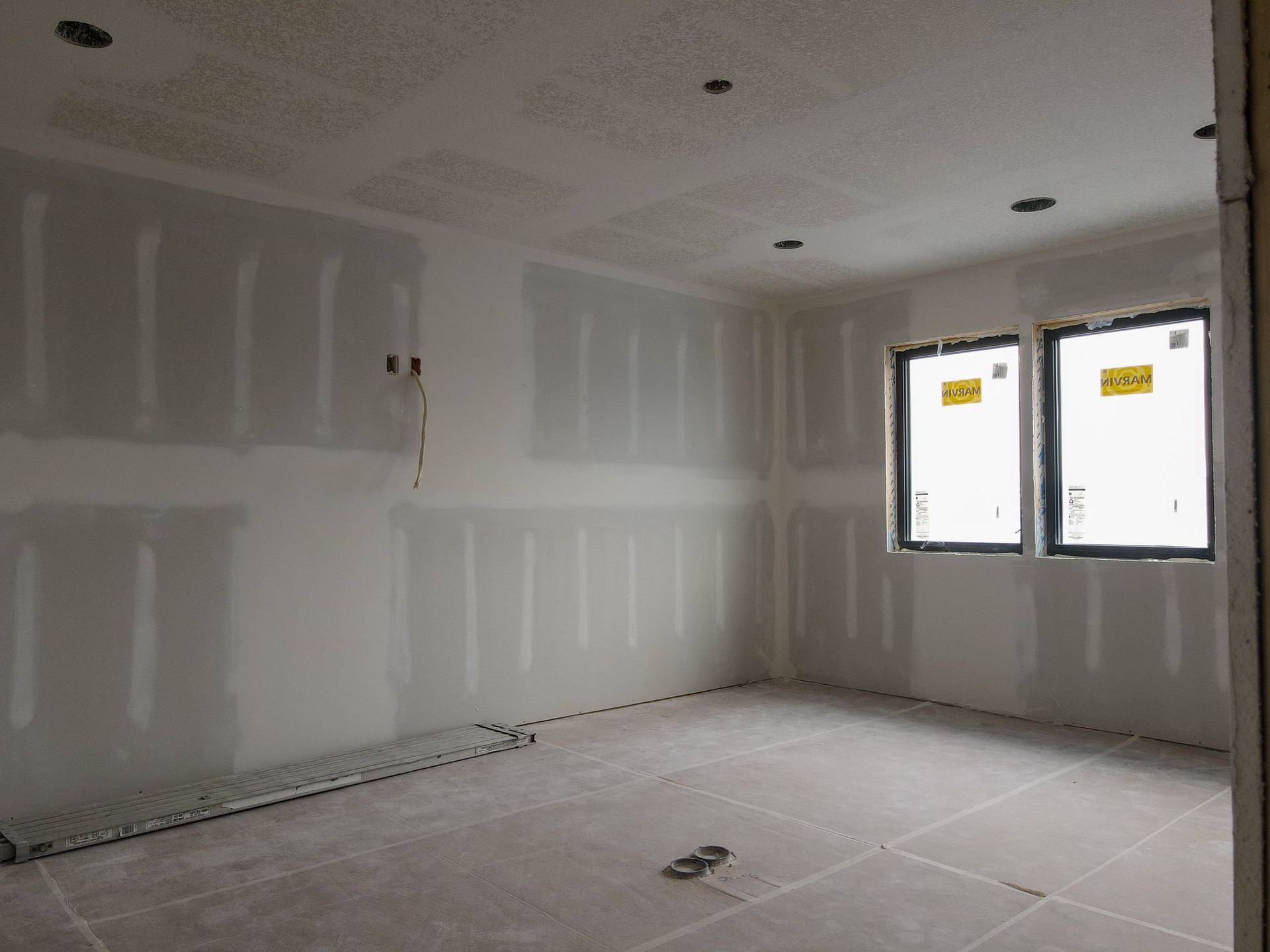 A room with a lot of drywall and two windows