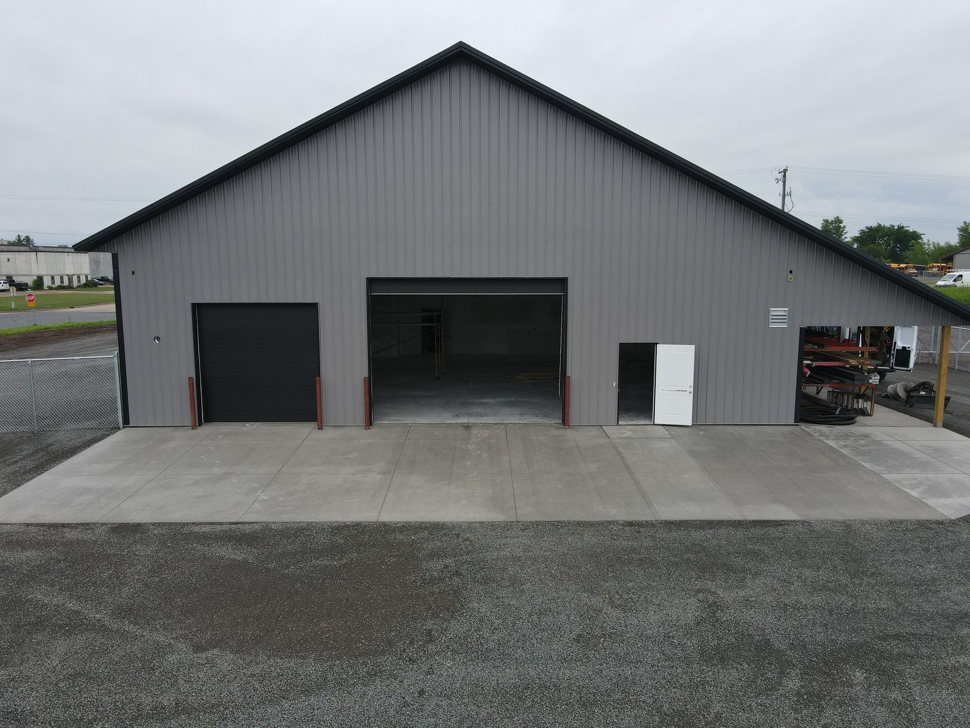 A large gray building with a black roof and a concrete driveway.