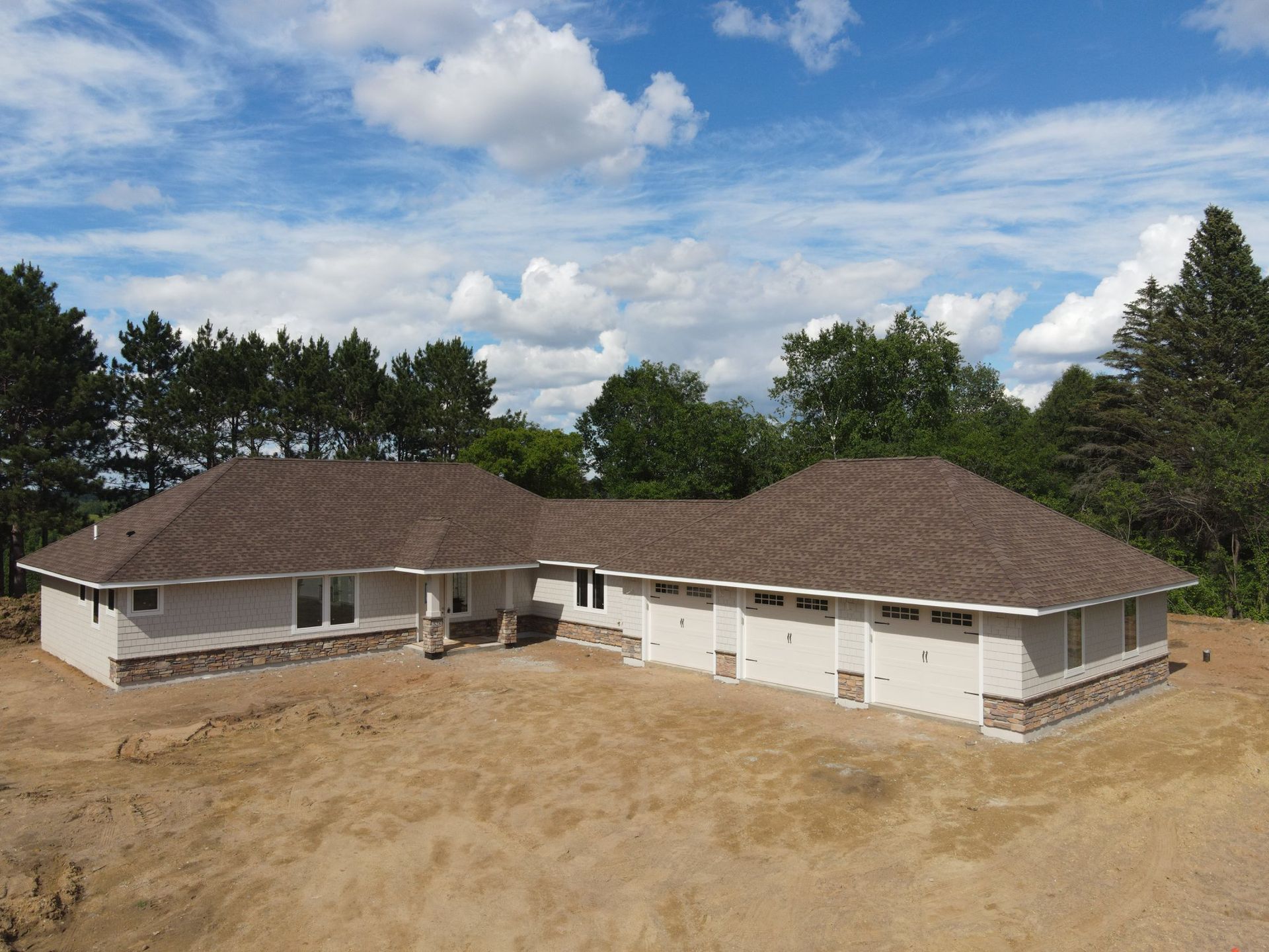 An aerial view of a white house with a brown roof
