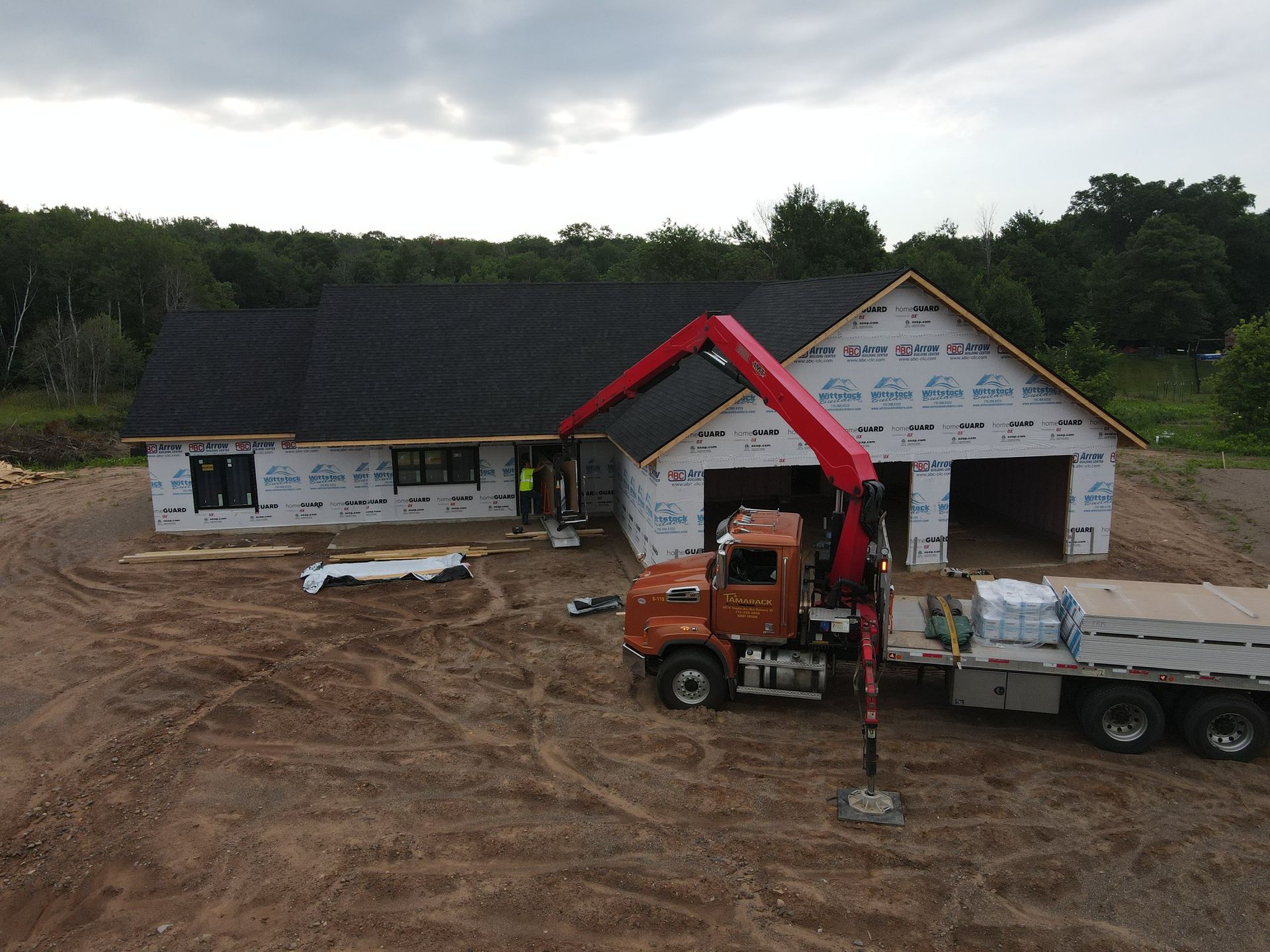 An aerial view of a truck with a crane attached to it in front of a house under construction.