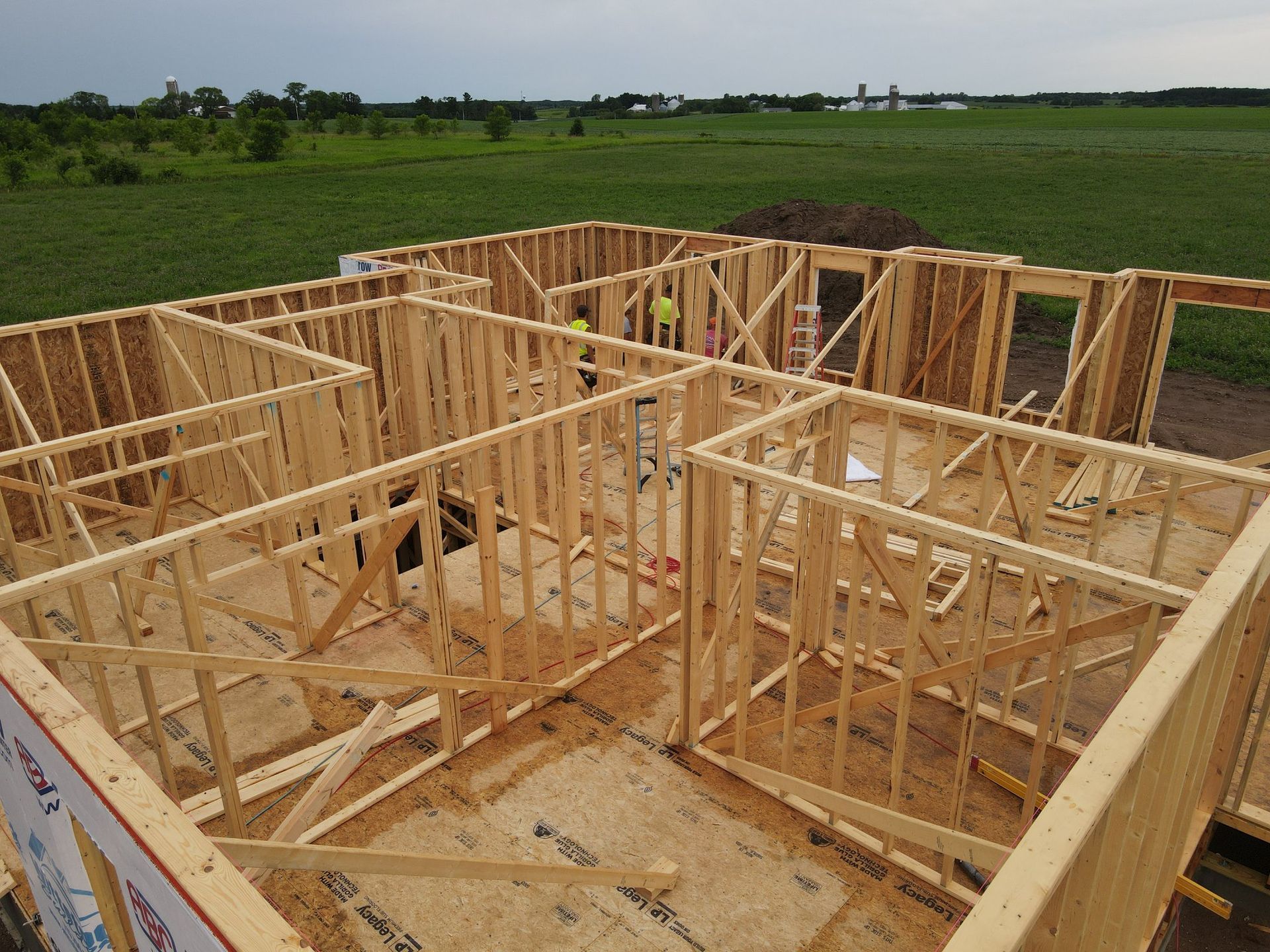 A wooden house is being built in a field.