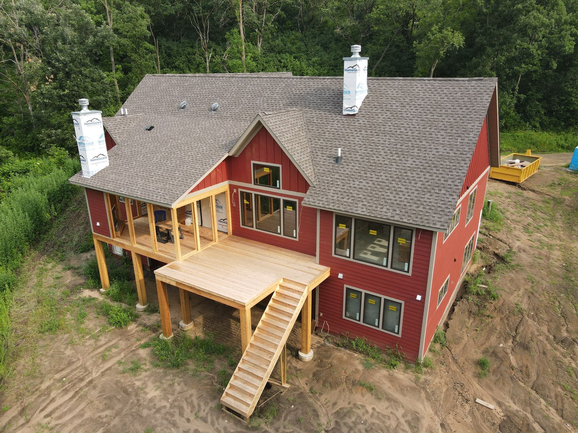 An aerial view of a red house with a deck and stairs.