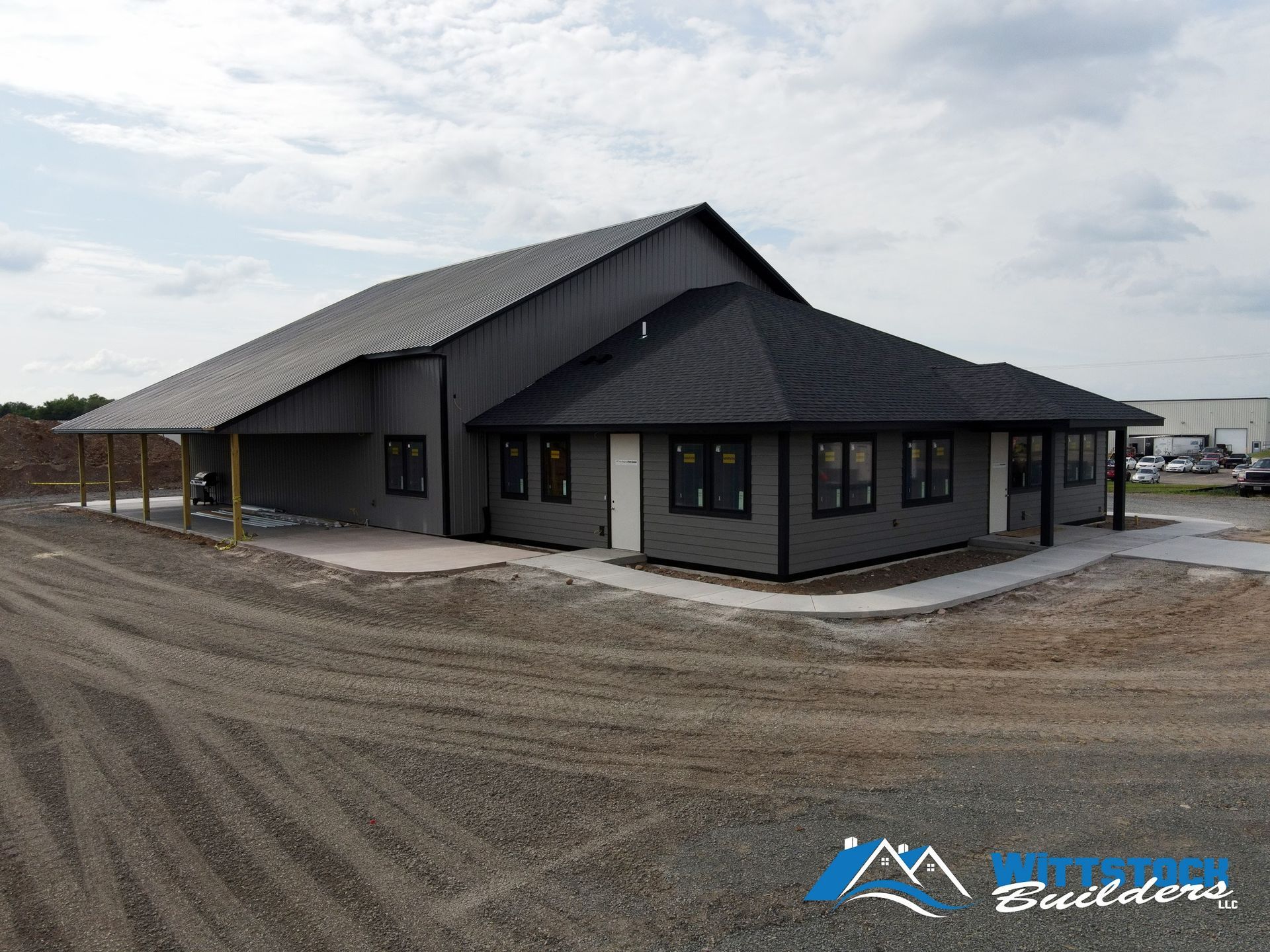 A large black building is sitting on top of a dirt field.