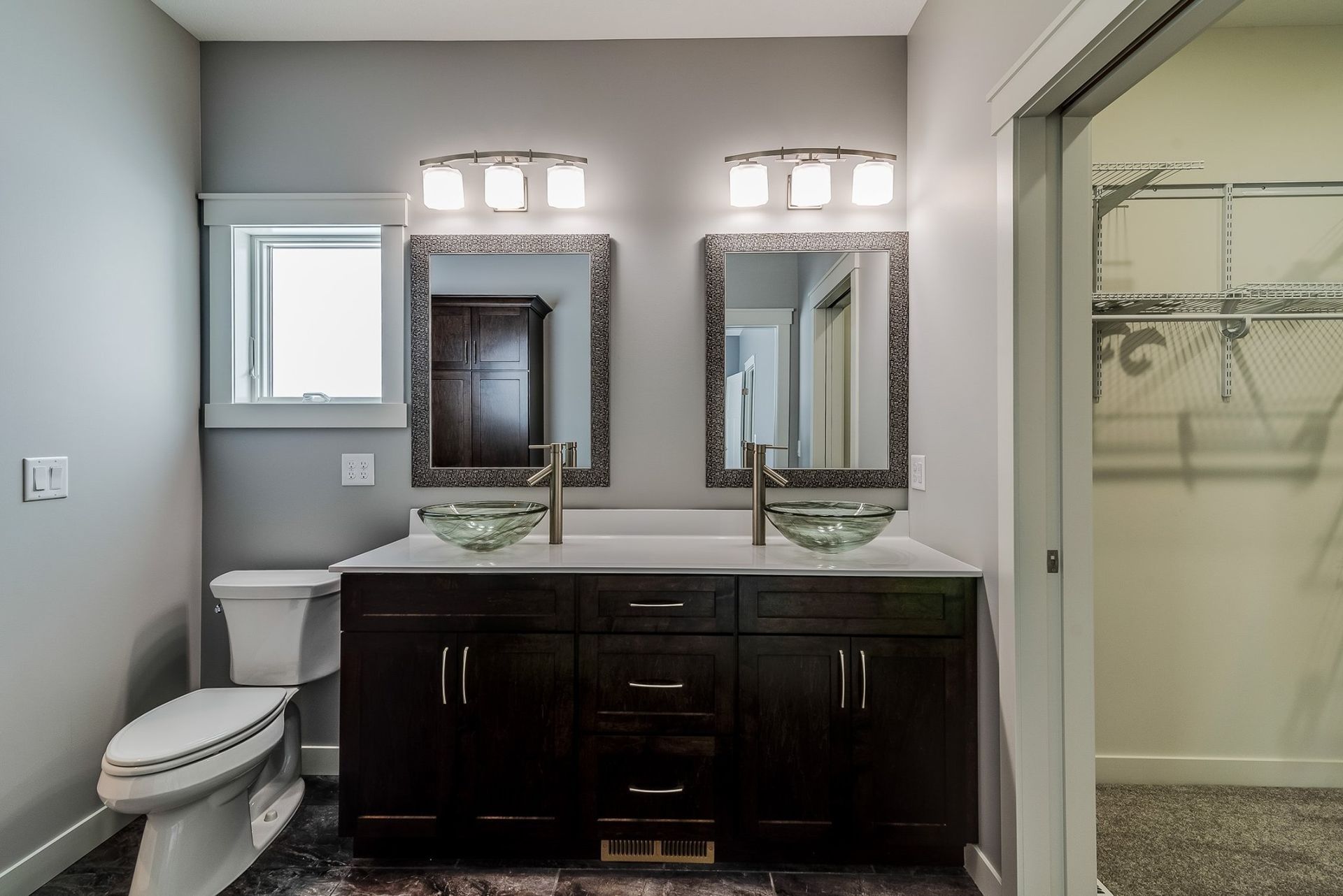 A bathroom with two sinks, a toilet, and two mirrors.
