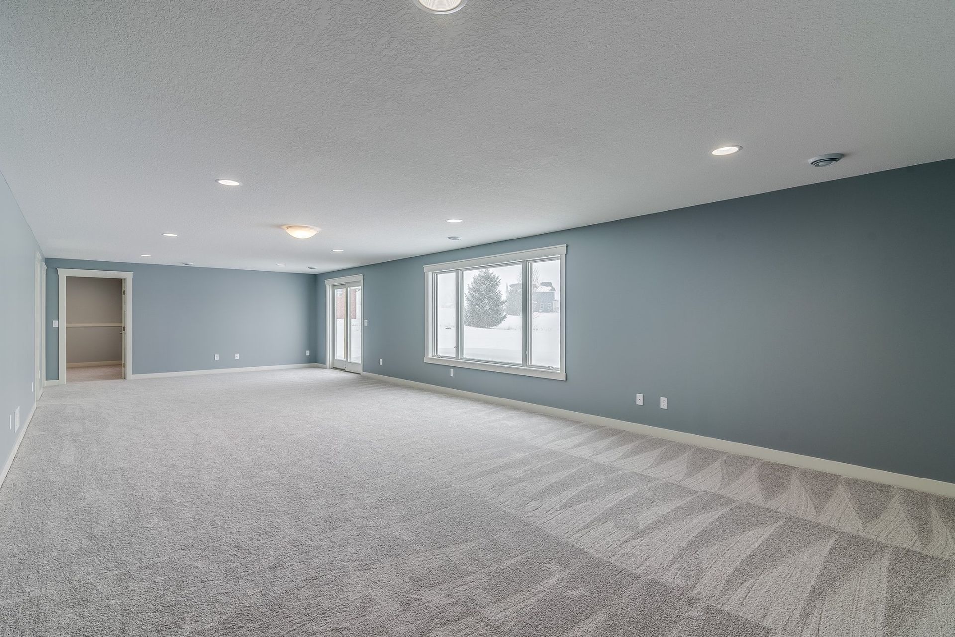 An empty basement with a lot of windows and carpet.