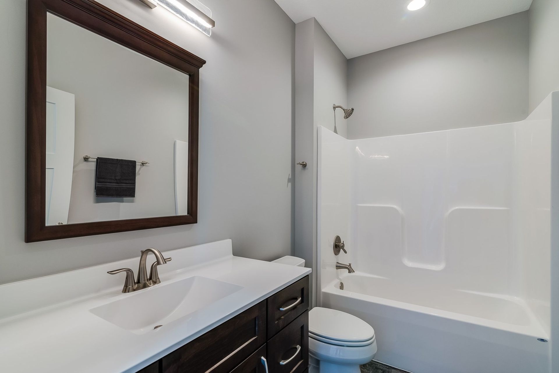 A bathroom with a toilet, sink, mirror and bathtub.