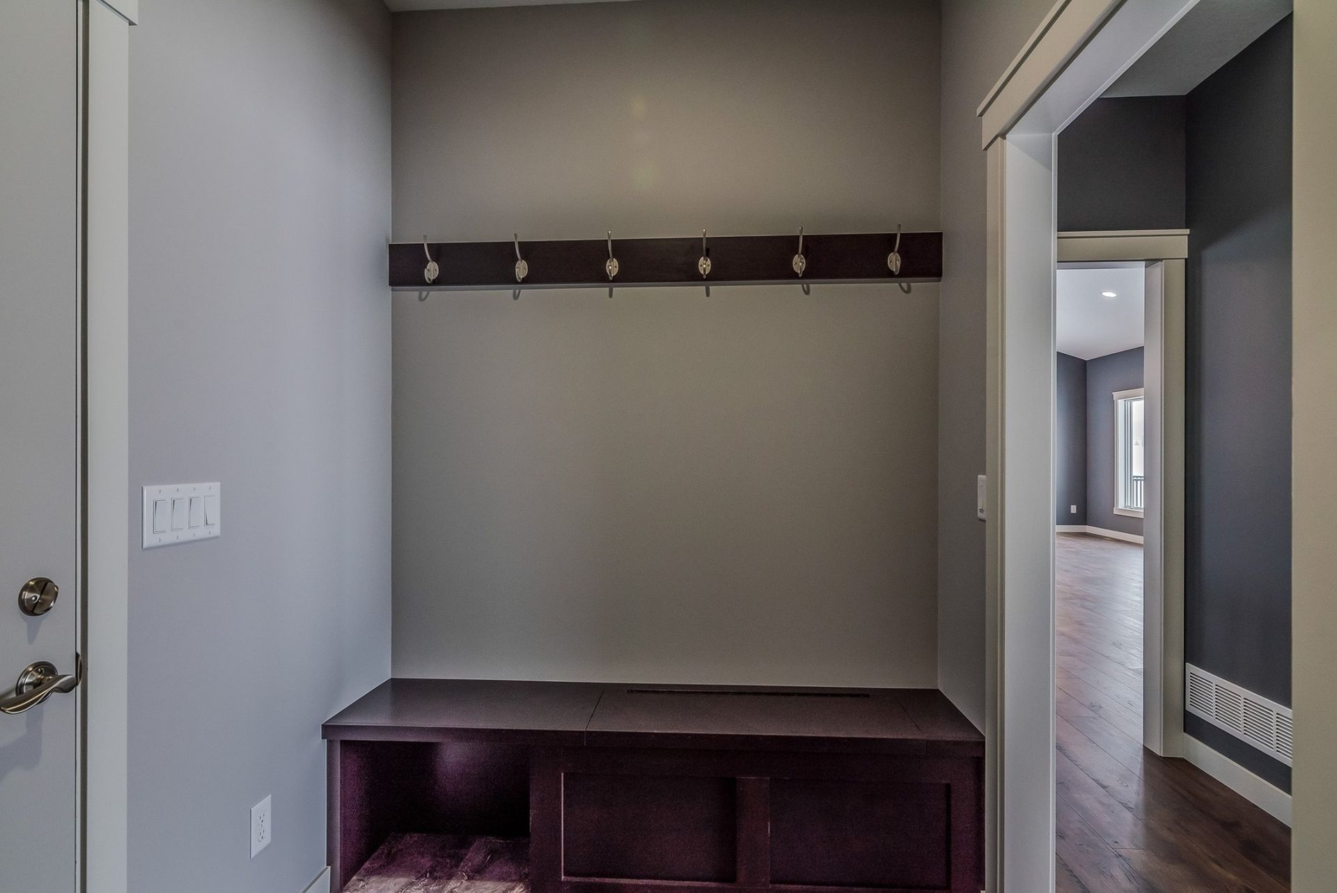 A hallway with a bench and hooks on the wall