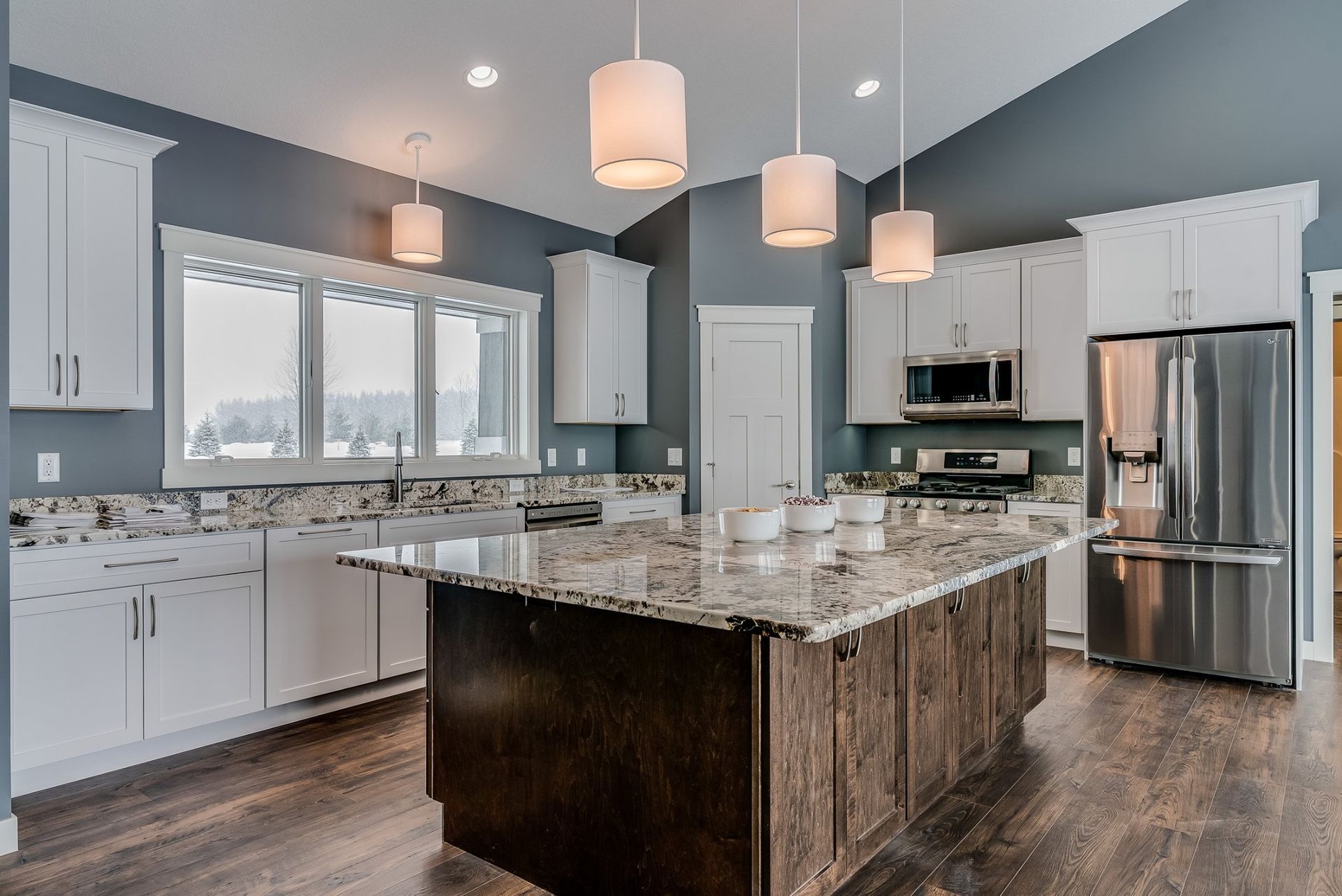 A kitchen with a large island in the middle and stainless steel appliances.